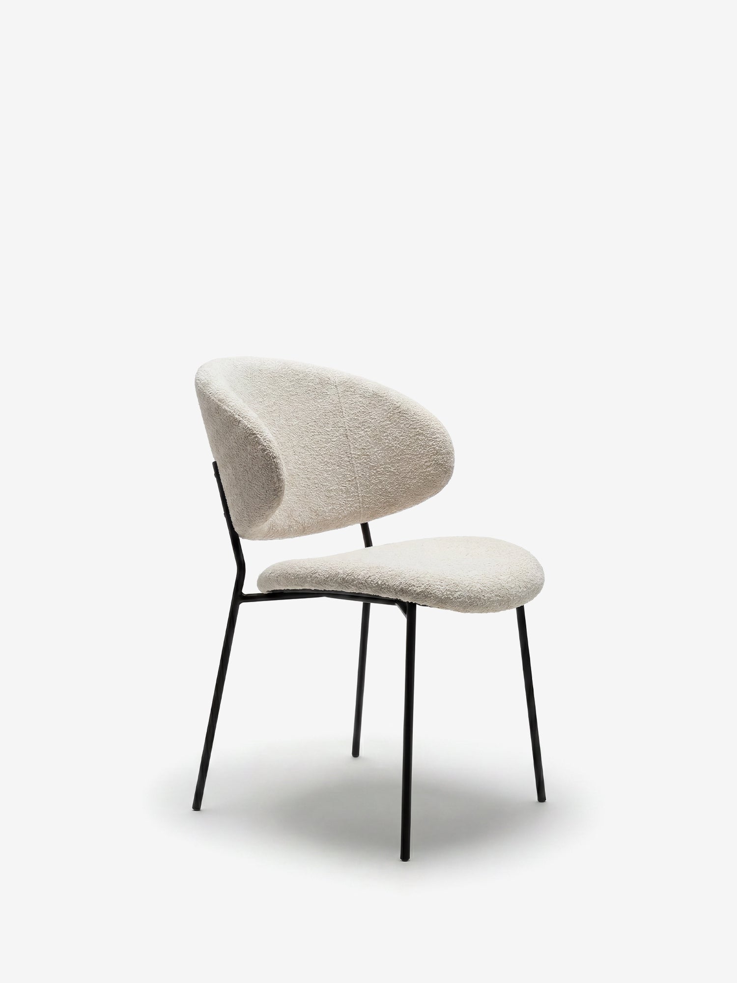 La sedia Bruma di Divani.Store presenta uno schienale imbottito e sinuoso rivestito in un elegante tessuto a trama, gambe in metallo nero e un design minimalista e aperto, perfetto per gli interni moderni.