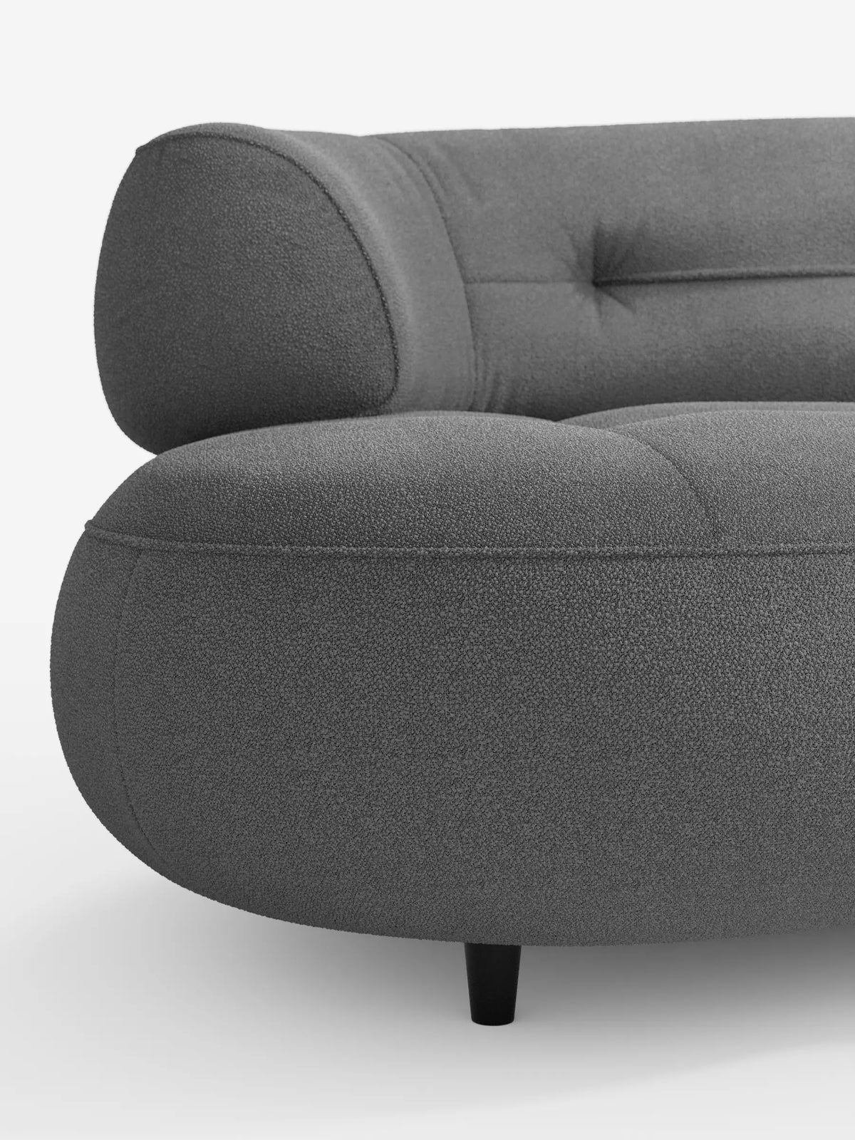 Un primo piano del divano Curvo a Fagiolo 3 posti “Croissant” in grigio antracite, con schienali traslanti rivestiti in morbido tessuto effetto cotone smacchiabile T33, caratterizzato da una silhouette curva e dal profilo ribassato, con cuscini morbidi su gambe minimaliste.