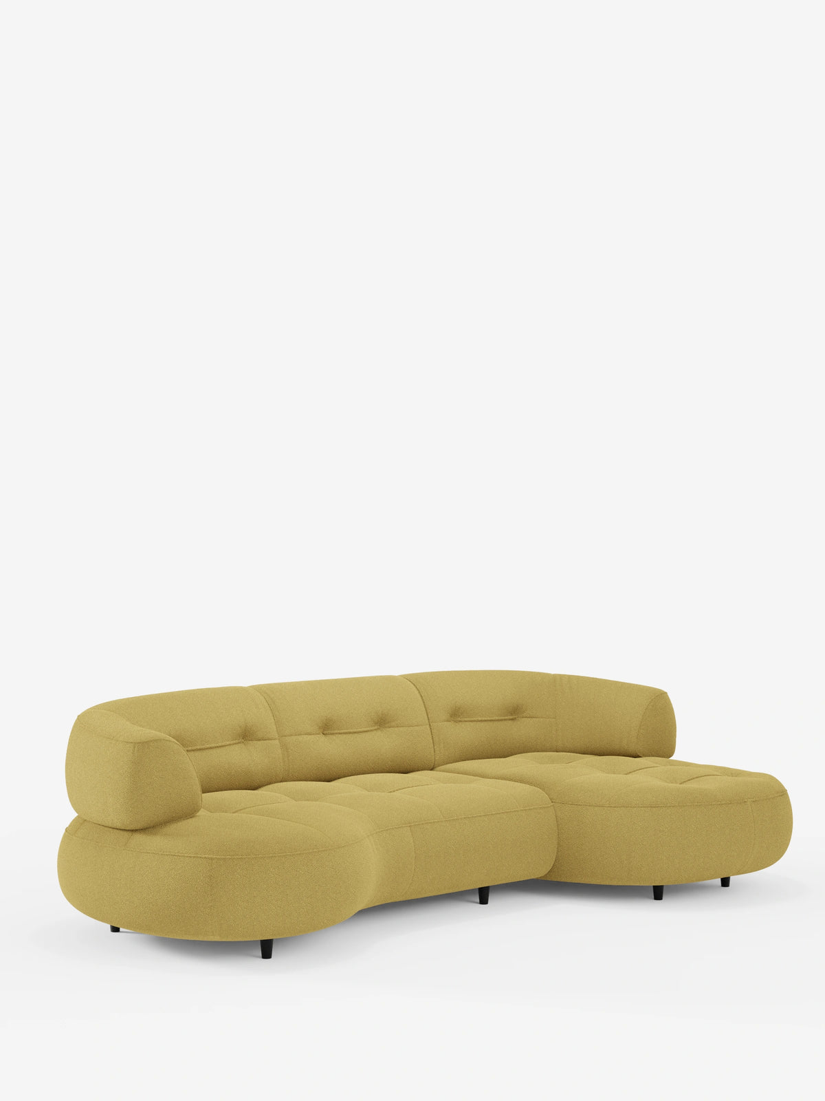 Un divano angolare Curved, a forma di fagiolo, con schienali scorrevoli rivestiti in morbido tessuto effetto cotone smacchiabile T33, rivestito in tessuto giallo senape con motivo trapuntato e gambe corte e cilindriche di colore scuro.