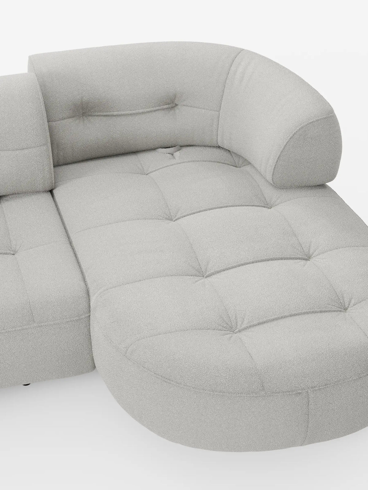 Un divano angolare “Croissant” di colore grigio chiaro, dal design a forma di fagiolo e con schienali scorrevoli, rivestito in morbido tessuto effetto cotone smacchiabile T33, caratterizzato da una seduta trapuntata e da uno schienale curvo con bordi arrotondati su sfondo bianco.