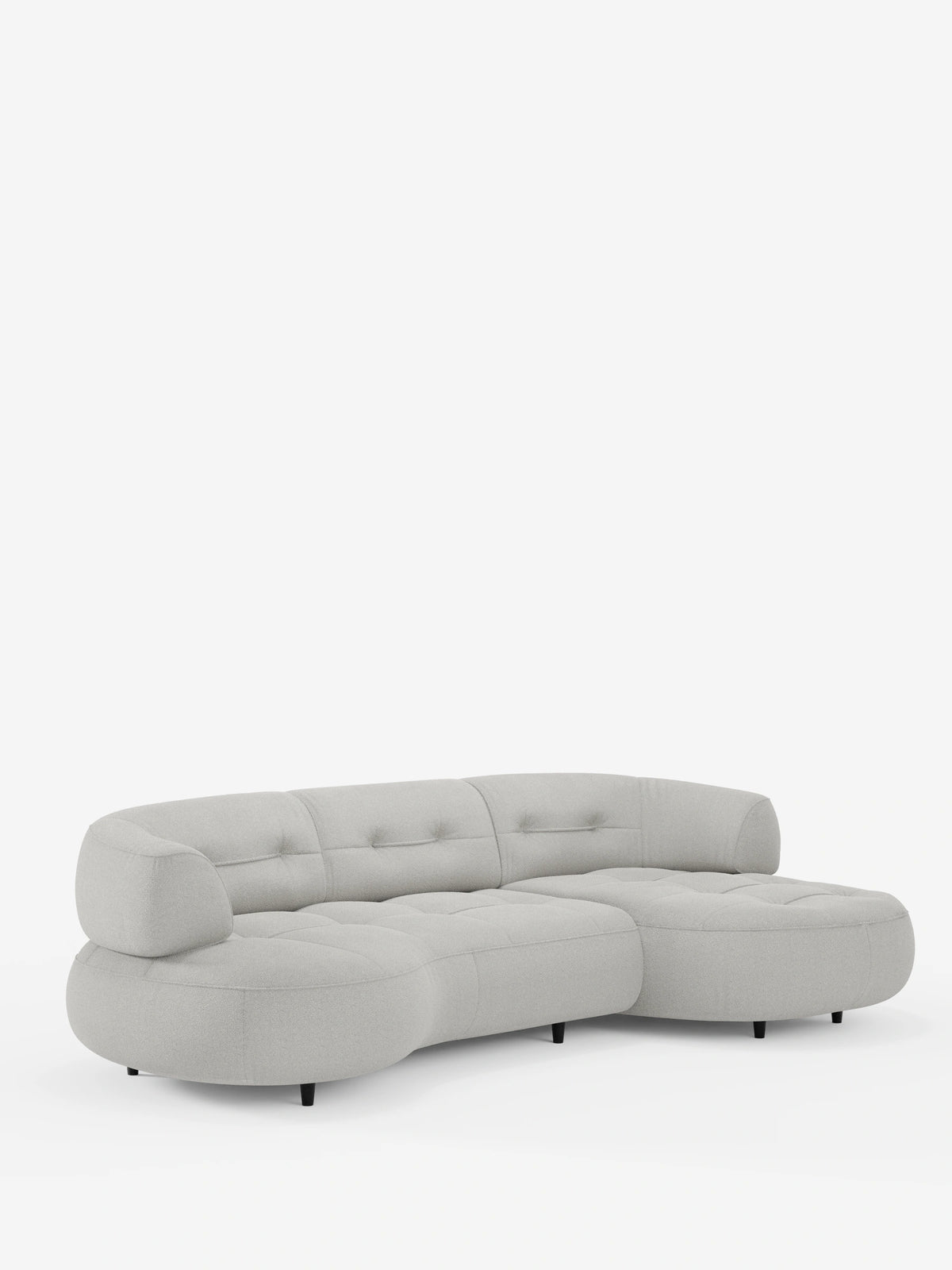 Un divano angolare Croissant di colore grigio chiaro, dal design a forma di fagiolo, con schienali scorrevoli in morbido tessuto effetto cotone smacchiabile T33, bordi arrotondati, cuscini trapuntati, gambe corte scure e una chaise longue sul lato destro.