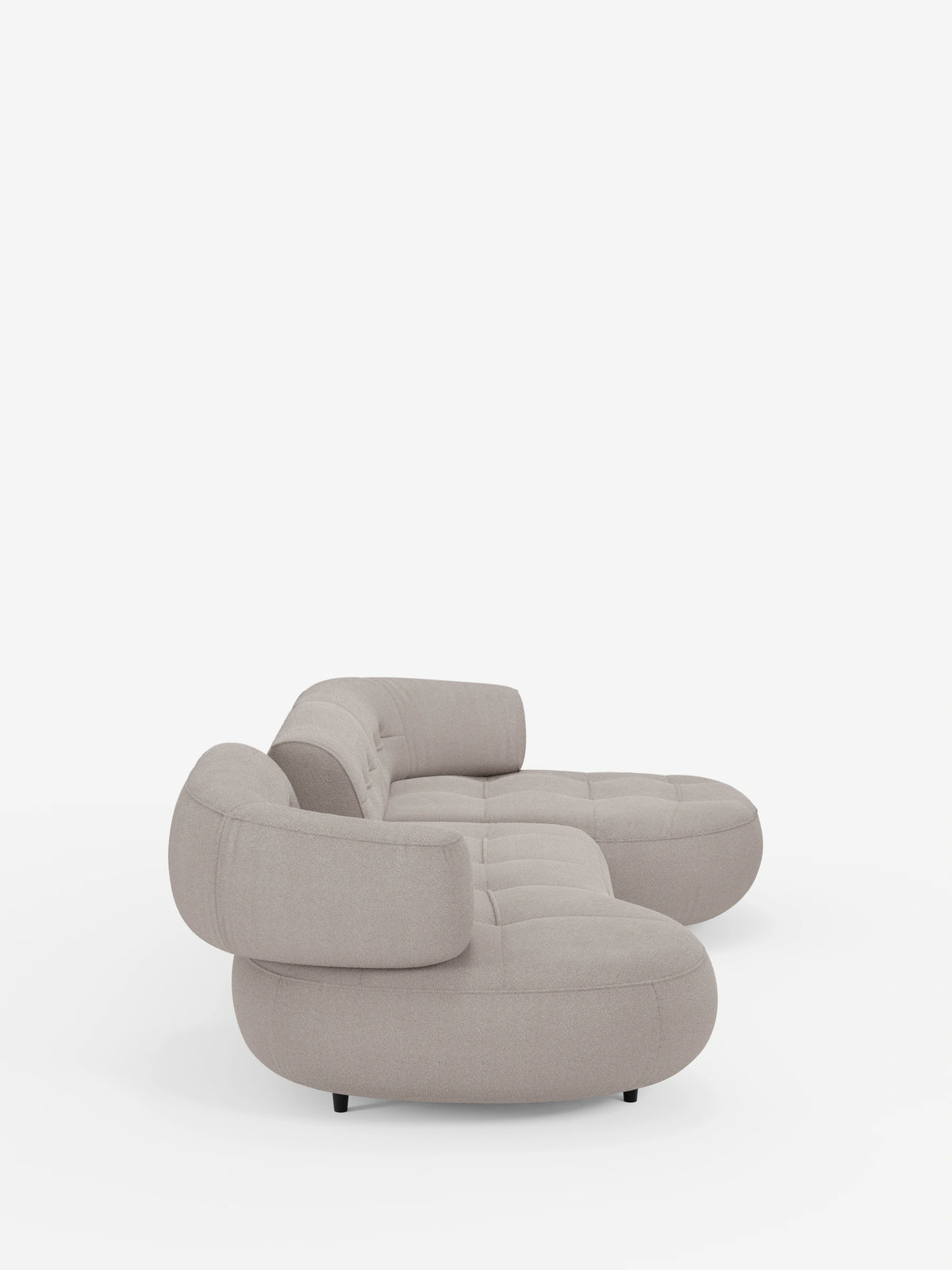 Un divano angolare Croissant color beige chiaro dal design a fagiolo e schienali regolabili in morbido tessuto effetto cotone smacchiabile T33, caratterizzato da una forma a fagiolo, cuscini trapuntati, schienali regolabili e gambe corte e scure su sfondo bianco.