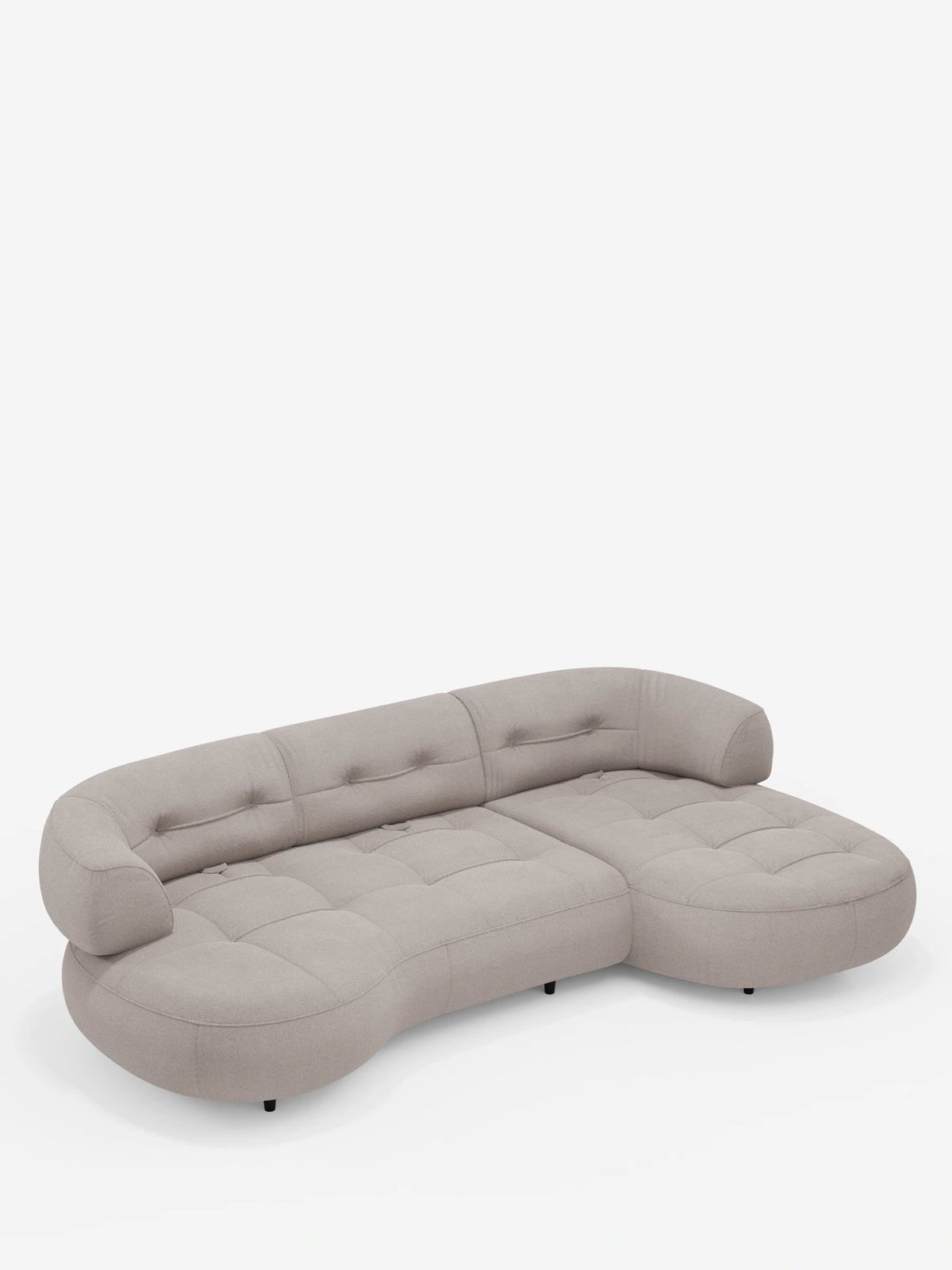 Un divano angolare Croissant dalle forme curve e a fagiolo, con schienali scorrevoli in morbido tessuto effetto cotone smacchiabile T33 color beige chiaro, caratterizzato da una seduta trapuntata, cuciture orizzontali e piedini bassi scuri su sfondo bianco.