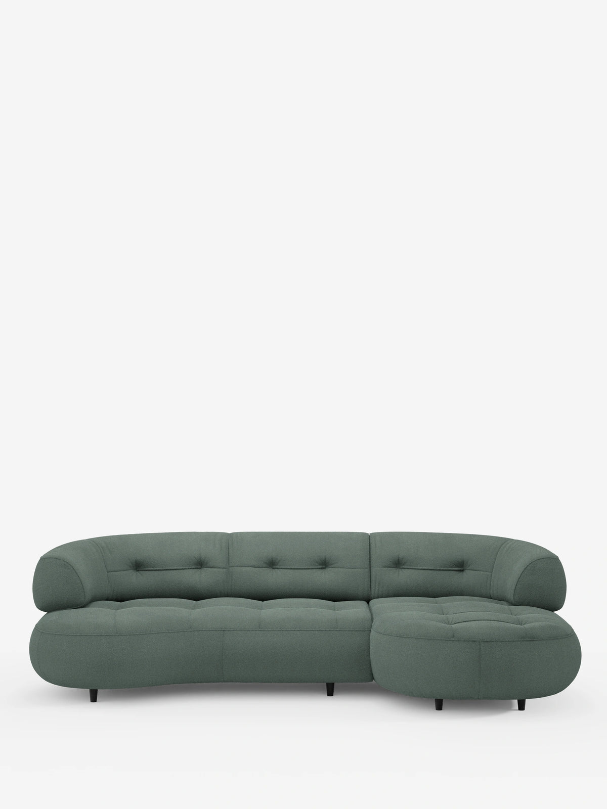 Un divano angolare “Croissant” color verde salvia, dalla forma a fagiolo, con schienali scorrevoli in morbido tessuto effetto cotone lavabile, modello T33, con rivestimento trapuntato e gambe cilindriche basse e scure su sfondo bianco.