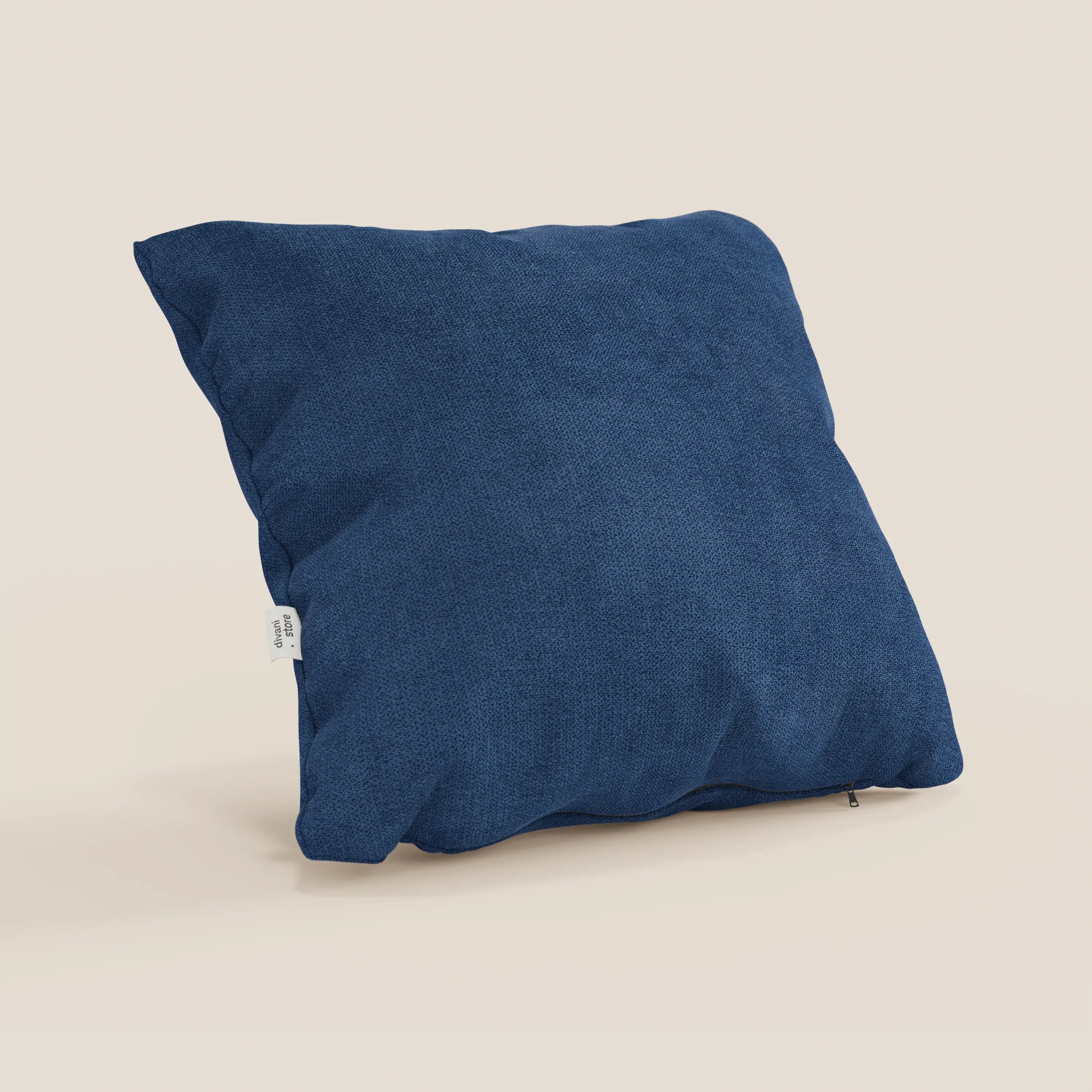 Il cuscino Destiny di Divani.Store, in colore blu T02 e tessuto morbido impermeabile, è appoggiato su uno sfondo beige chiaro. Una piccola etichetta bianca sulla cucitura sinistra ne completa l'aspetto accogliente e invitante.