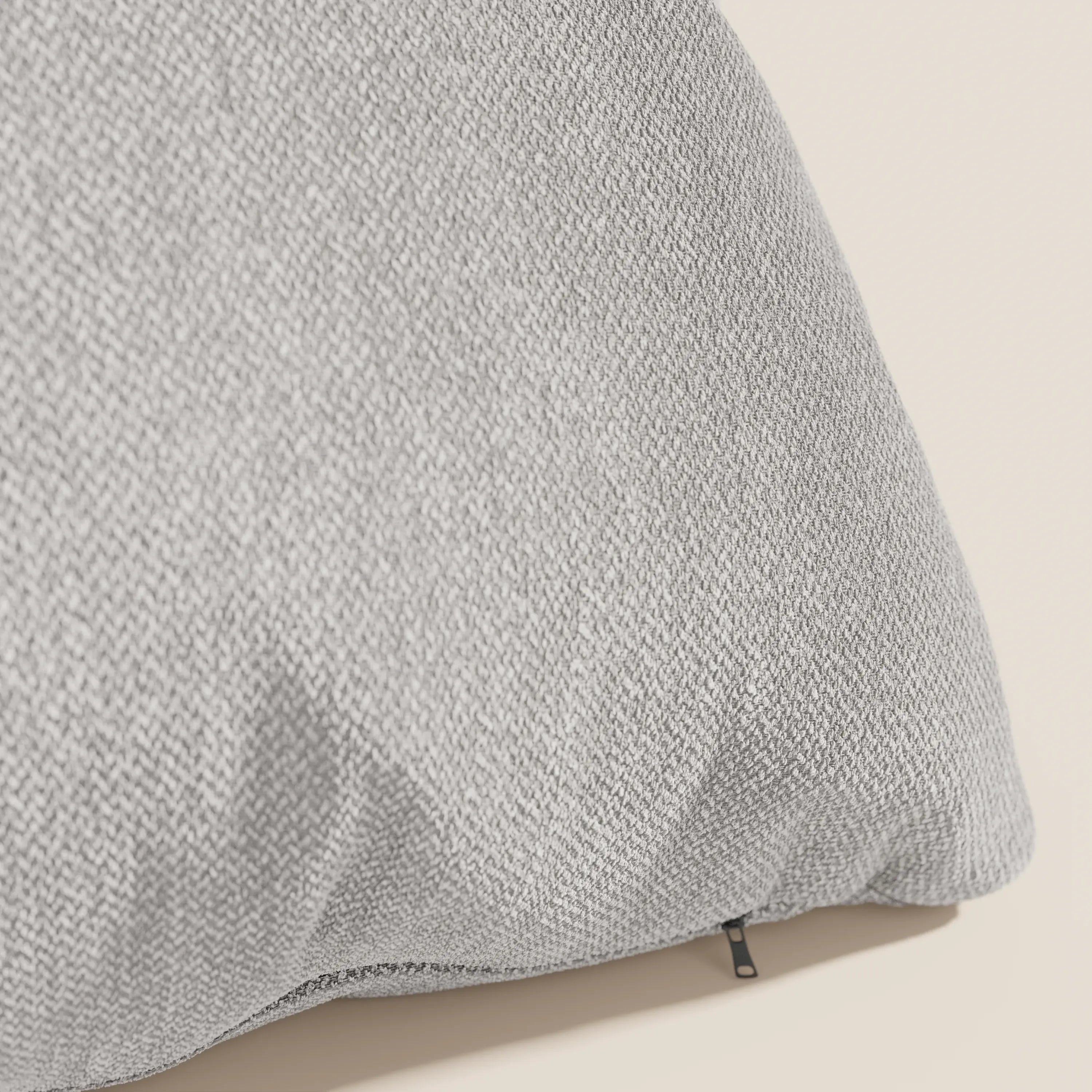 Primo piano di un cuscino Sogno di Divani.Store in tessuto SMACCHIABILE T05 grigio chiaro, caratterizzato da una sottile trama intrecciata e da una piccola cerniera nera: un cuscino elegante e minimale disponibile in vari colori per completare qualsiasi spazio moderno.