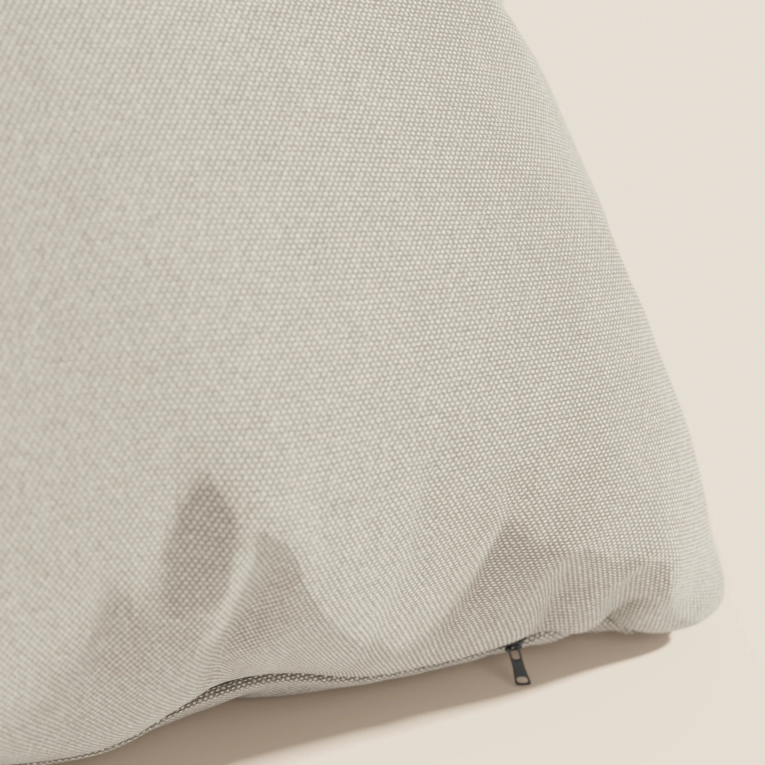Primo piano del cuscino Honey 45x45 cm di Divani.Store in tessuto simil cotone impermeabile T13 panna, con aspetto strutturato e grigio chiaro, cerniera a vista e fodera lavabile su fondo panna. Disponibile in diversi colori.