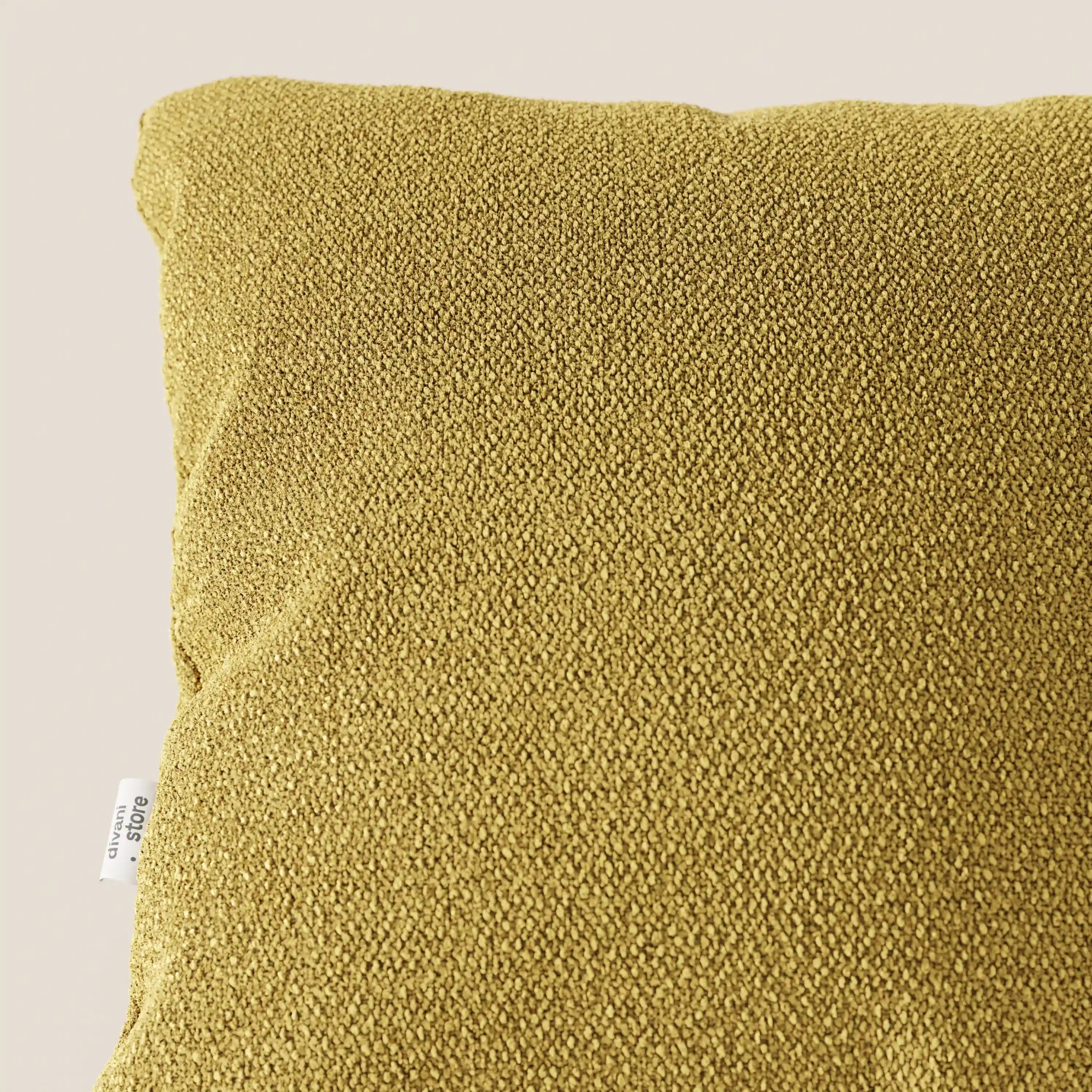 Primo piano del cuscino Lambada verde oliva di Divani.Store, realizzato in fresco tessuto di cotone naturale T33 antimacchia e impermeabile. L'immagine evidenzia la trama intrecciata e l'etichetta bianca in alto a sinistra.
