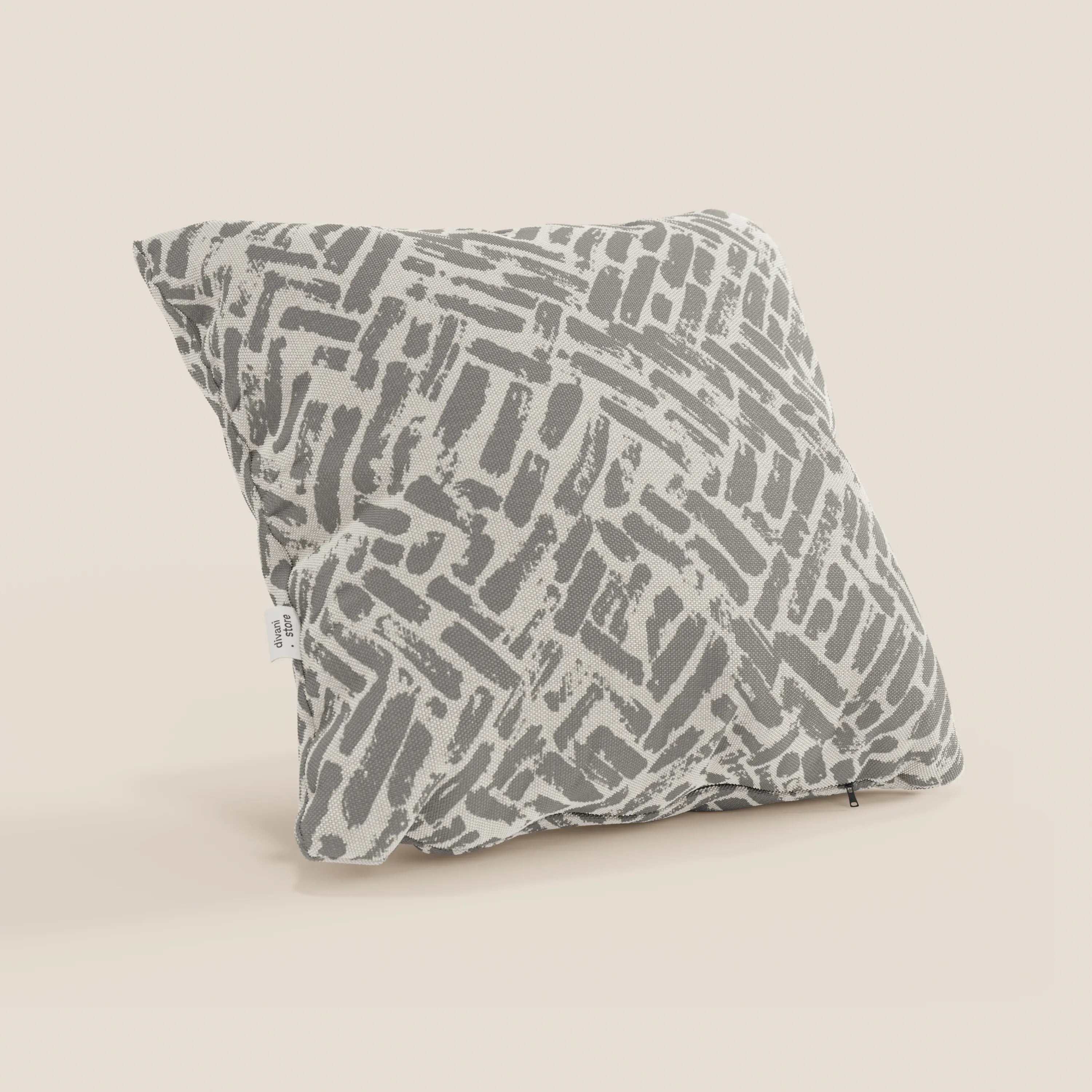 Il cuscino geometrico Brick di Divani.Store è un cuscino decorativo quadrato realizzato in tessuto grigio idrorepellente, caratterizzato da un disegno strutturato. Poggia su una superficie beige chiaro, con una piccola etichetta bianca sulla cucitura sinistra.
