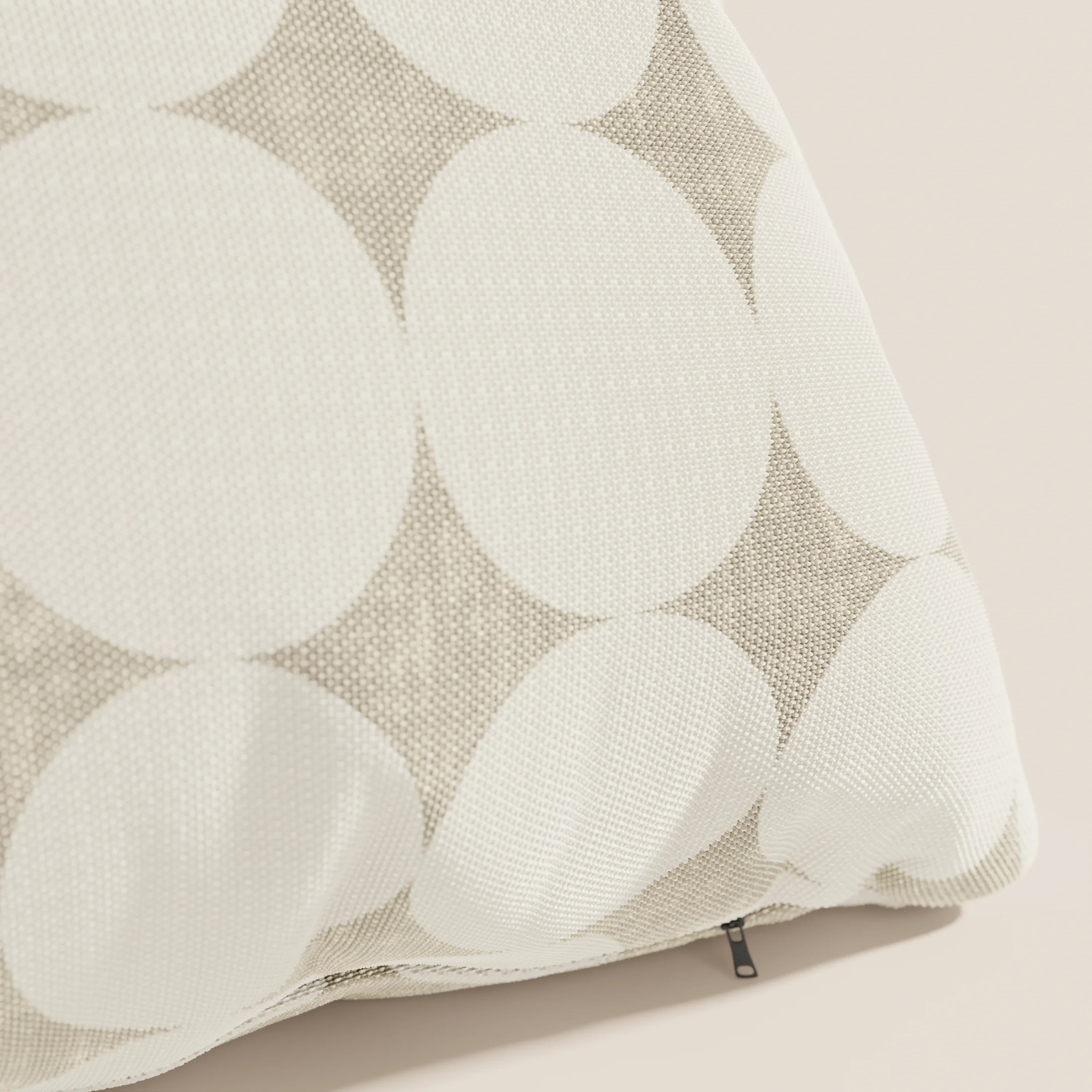 Primo piano dei cuscini geometrici Dot di Divani.Store, caratterizzati da un coperchio Idrorepellente bianco con grandi cerchi bianchi sovrapposti su beige e da una cerniera nera a vista: una scelta di stile tra i cuscini decorativi.