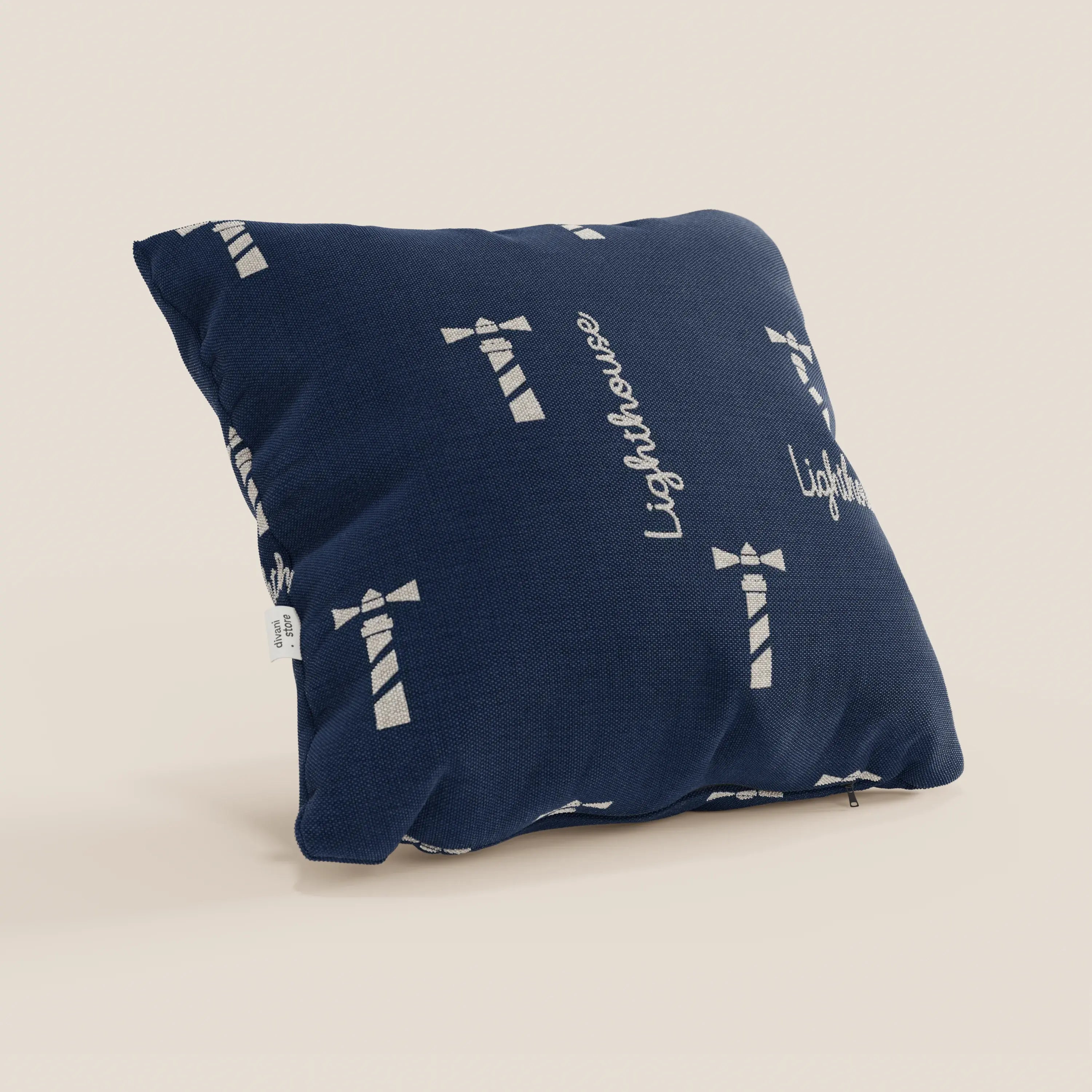 Nautilus collezione di cuscini stile marino di Divani.Store: cuscino quadrato blu navy in tessuto impermeabile faro, con illustrazione di un faro bianco, "Lighthouse" in corsivo, una piccola etichetta laterale bianca e cuscino lavabile. Esposto su sfondo beige.