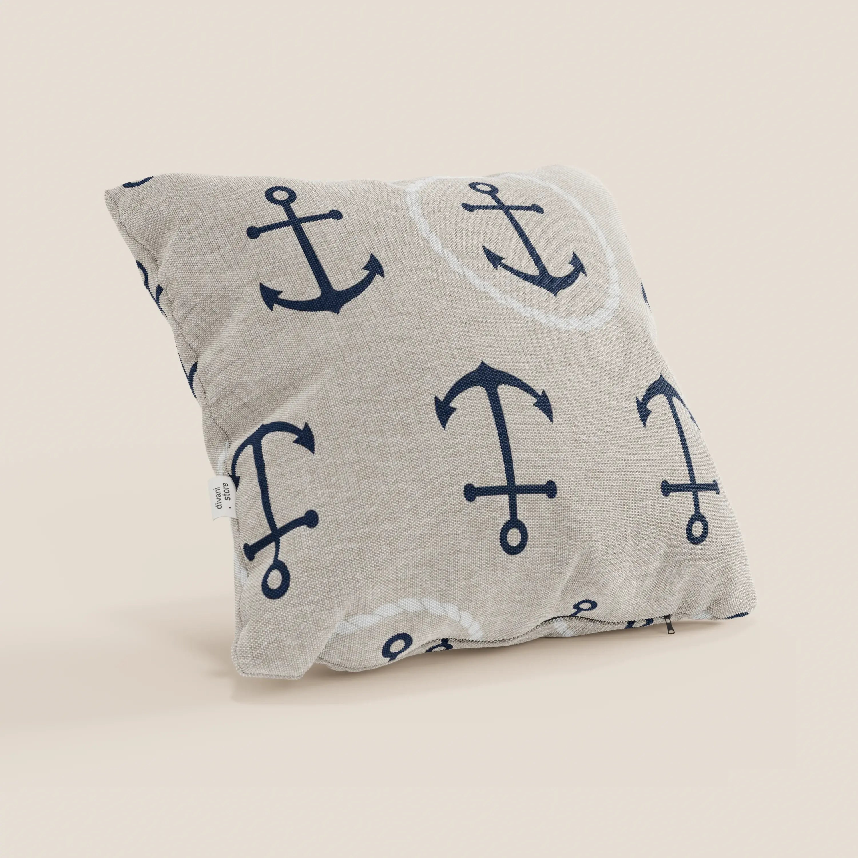 Il cuscino quadrato beige Nautilus di Divani.Store, con motivi ancora blu navy e cerchi di corda bianchi, ha zip inferiore e piccola etichetta bianca. È lavabile in lavatrice, ideale per uno stile marino pratico ed elegante.
