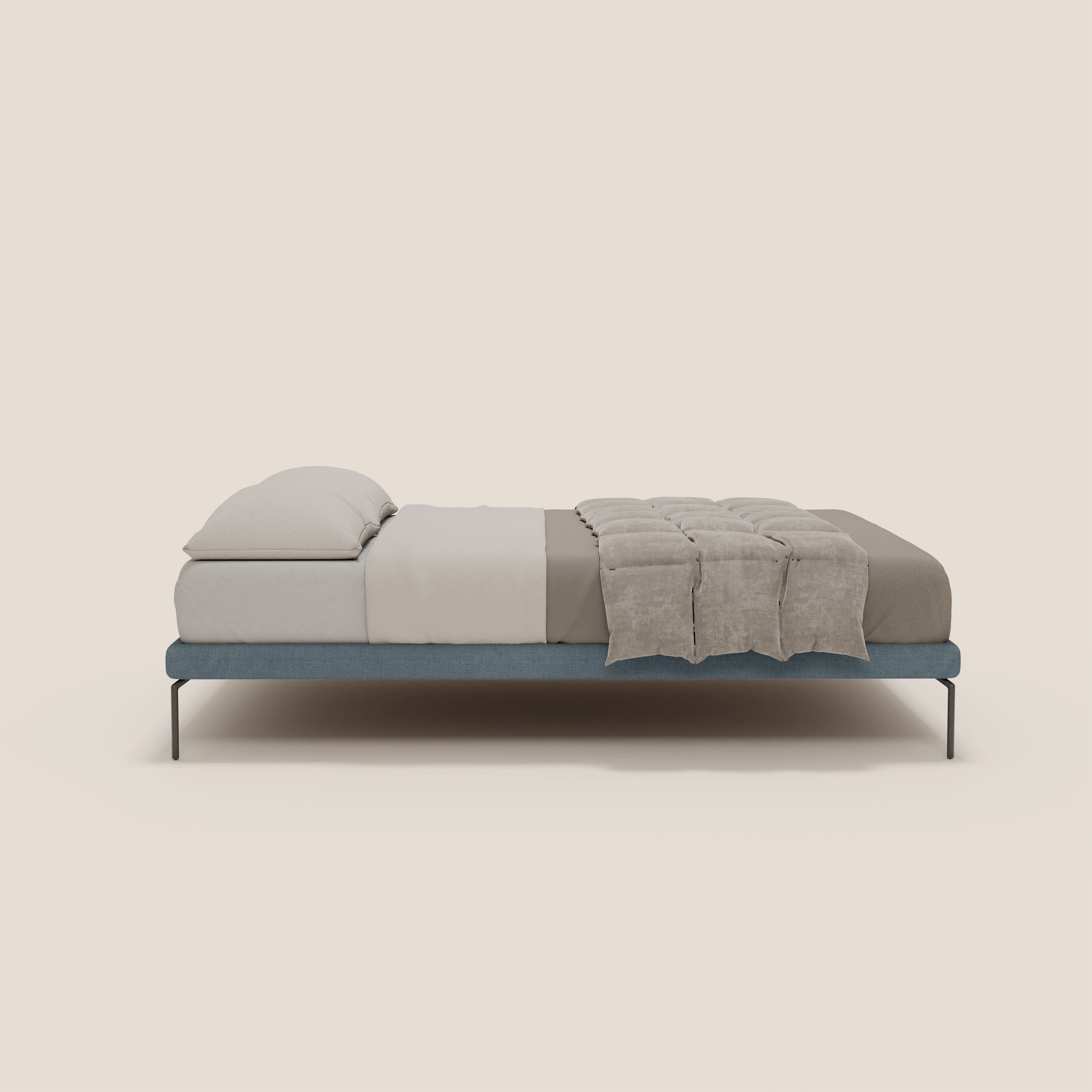 Il sommier sfoderabile Letti.store Ring ha una struttura alta 24 cm in tessuto impermeabile T14 carta da zucchero, ordinatamente vestita di beige e tortora con due cuscini impilati, una coperta ripiegata tortora e sottili gambe nere su uno sfondo chiaro.