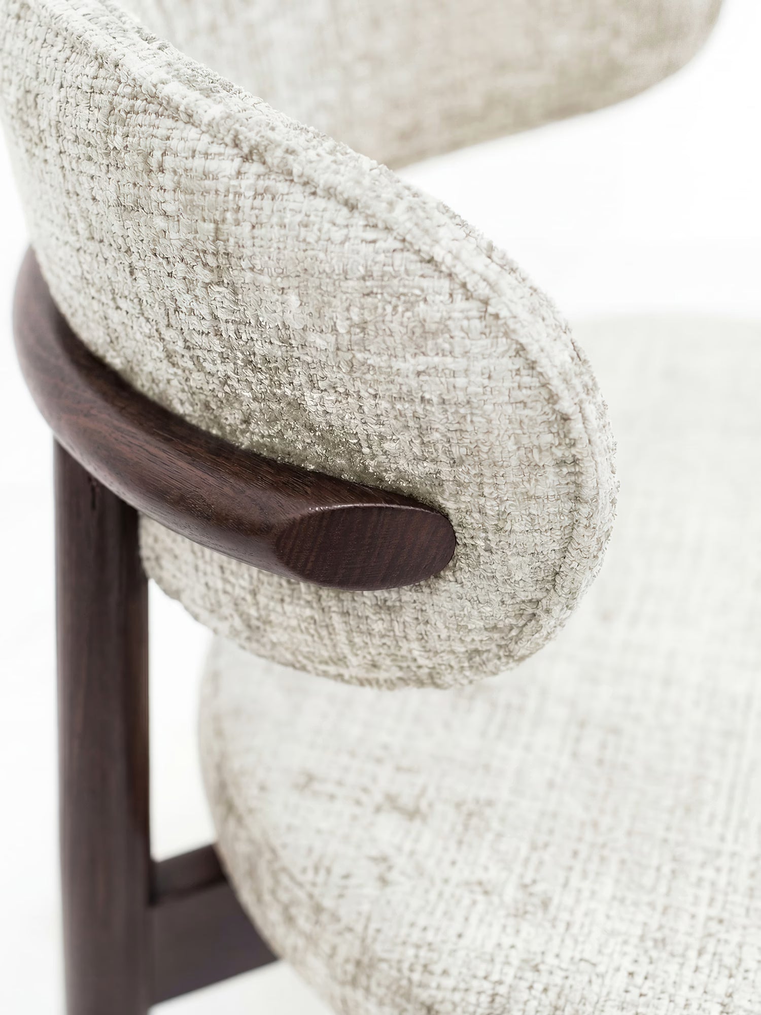 Primo piano della sedia imbottita Dafne di Divani.Store: presenta un tessuto chenille OEKO-TEX® beige chiaro e testurizzato sullo schienale e sulla seduta curvi, che crea un contrasto suggestivo con il legno liscio e massiccio di wengé.