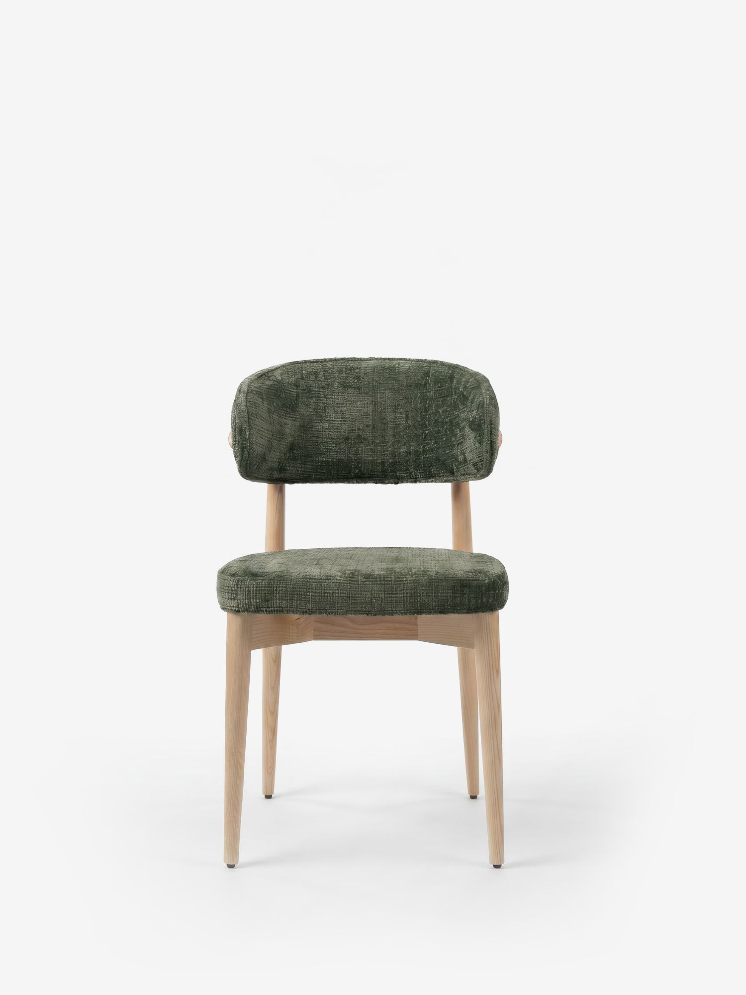La sedia imbottita Dafne di Divani.Store presenta una struttura in rovere naturale massiccio e un rivestimento in ciniglia certificata OEKO-TEX® di colore verde, con un'imbottitura morbida e uno schienale ricurvo. Il suo design minimalista risalta su uno sfondo bianco a tinta unita.