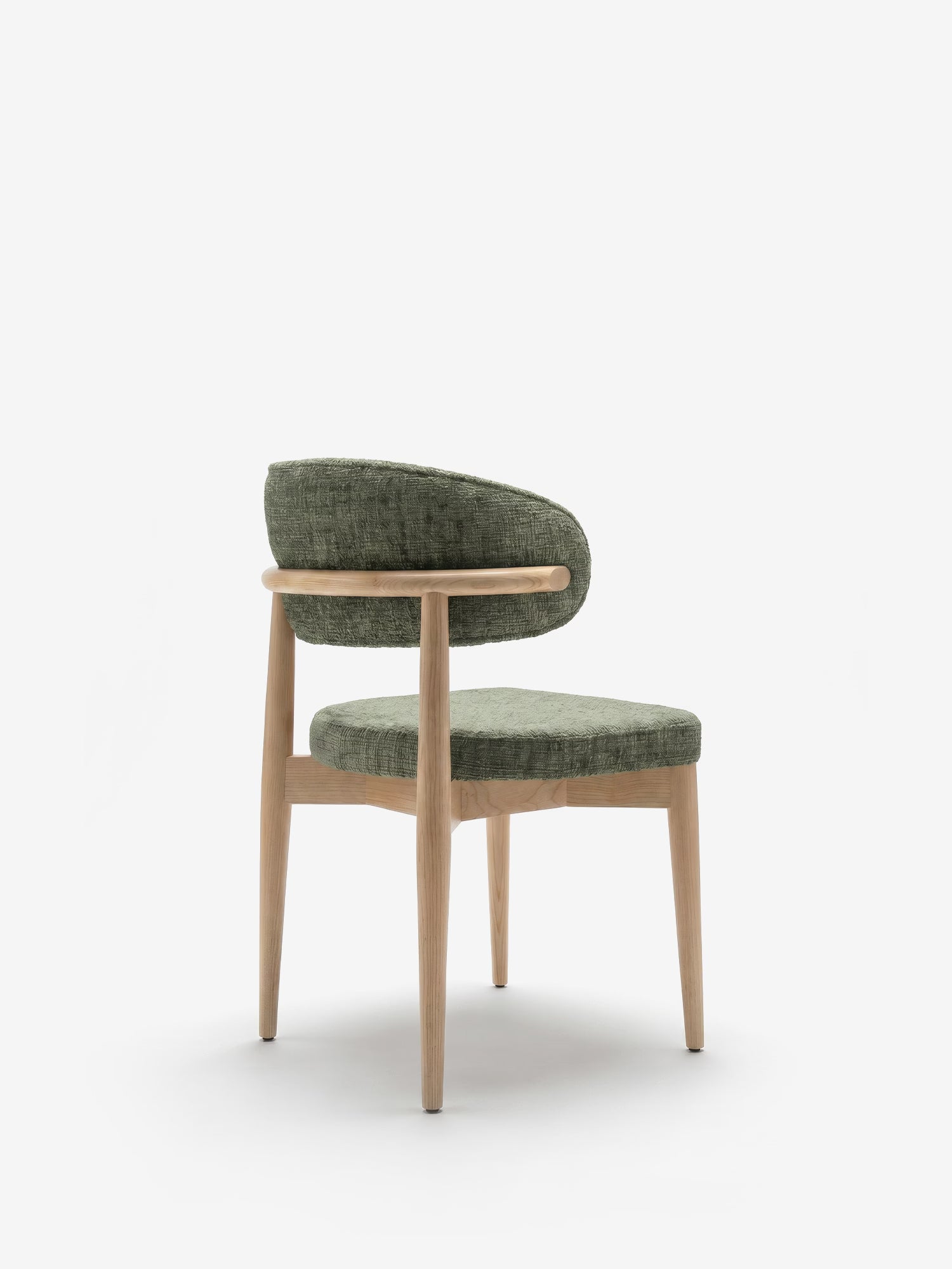 La sedia imbottita Dafne di Divani.Store presenta uno schienale ricurvo, una seduta in tessuto ciniglia certificato OEKO-TEX® in una tonalità di verde tenue e gambe e struttura in rovere massello naturale, il tutto messo in risalto da uno sfondo bianco a tinta unita per un look minimalista.
