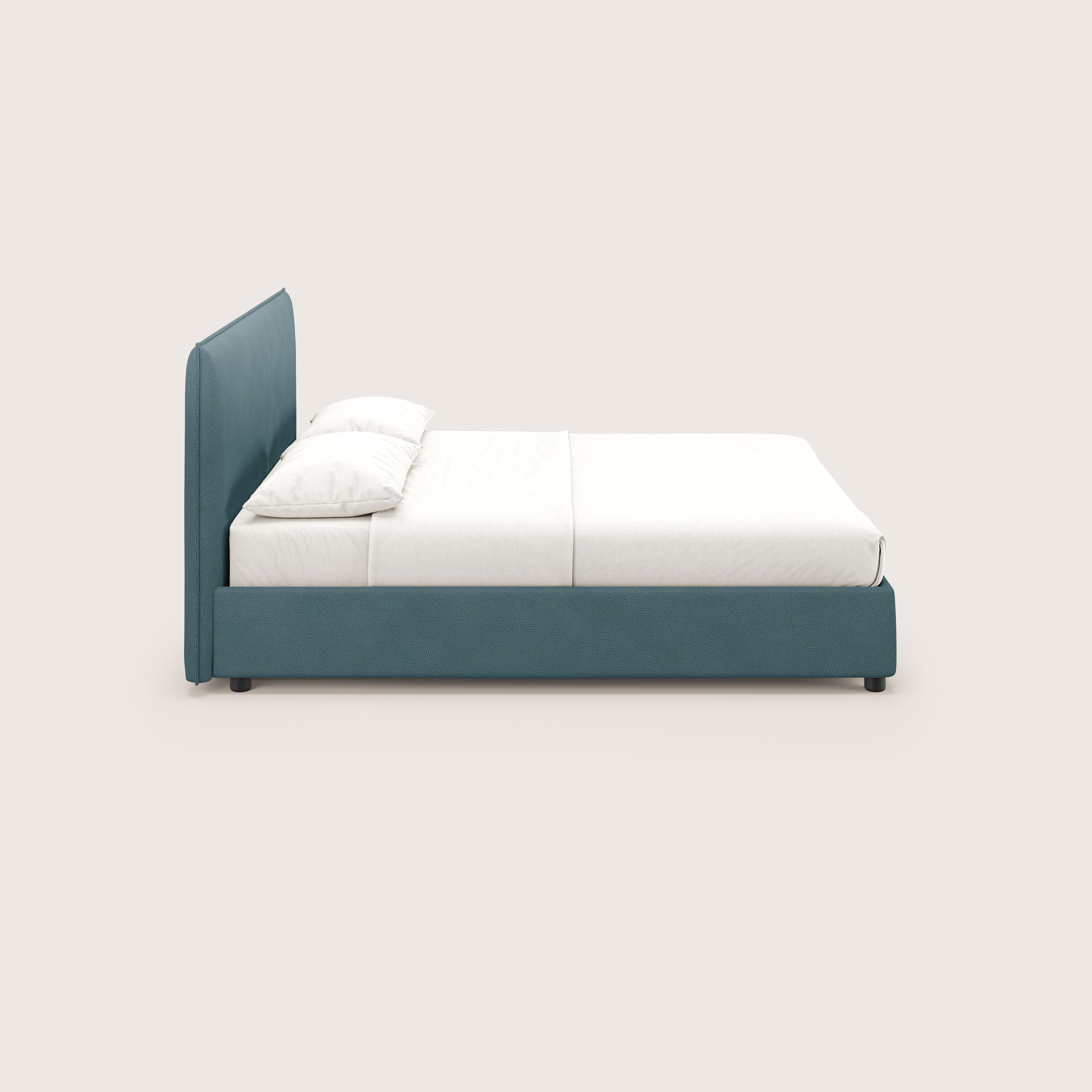 Una vista laterale minimalista del letto contenitore Nina di Letti.store, con struttura e testiera in microfibra antimacchia color verde acqua, lenzuola bianche e due cuscini bianchi. Il design italiano pulito si staglia su uno sfondo beige chiaro.
