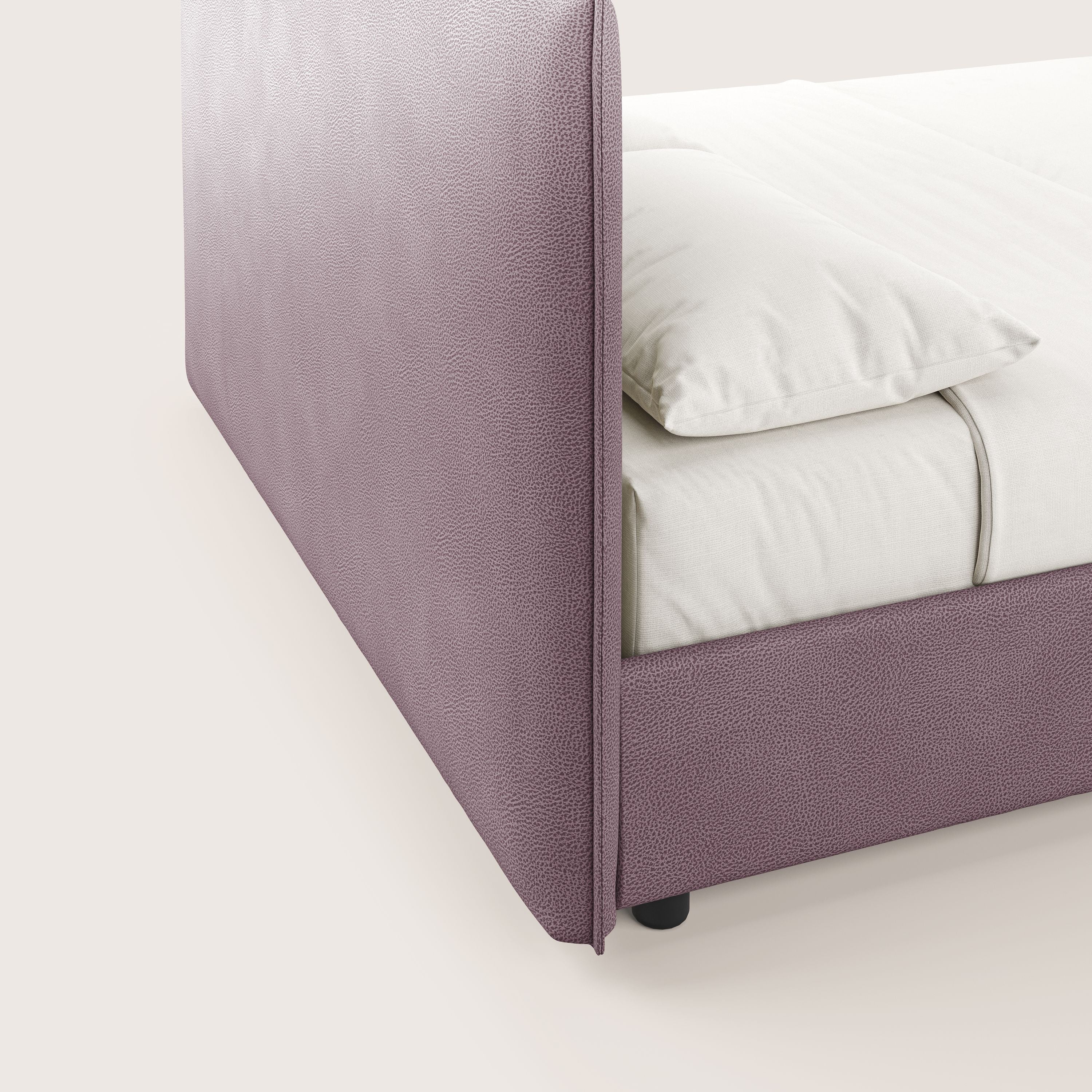 Primo piano di Nina letto contenitore di Letti.store: design minimale in microfibra di ecopelle antimacchia, tonalità rosa, con testata strutturata. Presentato con lenzuola e cuscini di colore bianco sporco, appoggiato su piccole gambe nere.