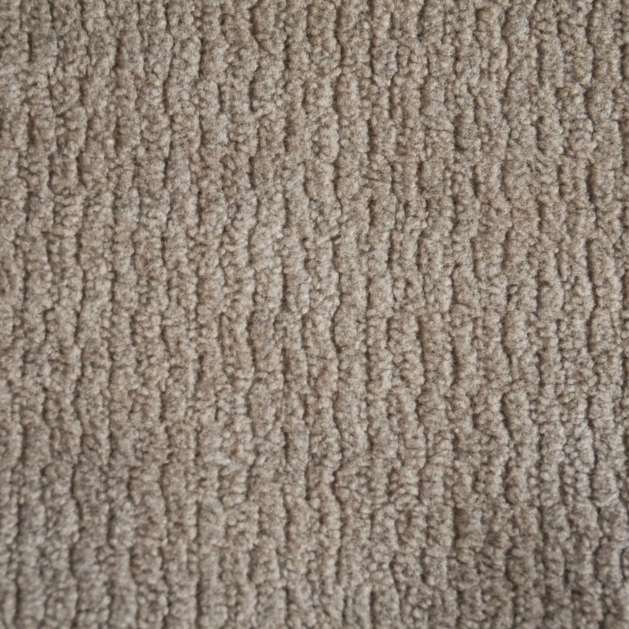Primo piano di Personalizzazione in T32 di Divani.Store: un tappeto beige con motivo ad anello e texture. Le fibre a trama fitta formano file verticali e ondulate, creando una superficie morbida, densa e uniforme in una leggera tonalità neutra.