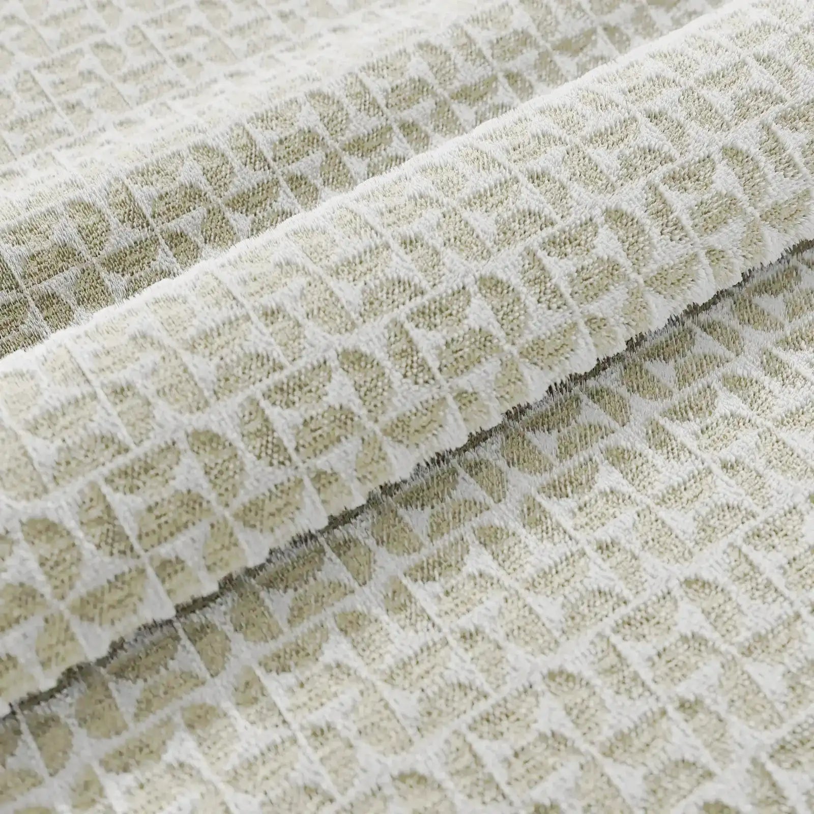 Primo piano del tessuto di lino color crema del cuscino decorativo Naxos 45x45 di Divani.Store, che presenta una trama geometrica a nido d'ape con quadrati in rilievo. Le delicate pieghe mettono in risalto la griglia tridimensionale e l'elegante design di questo cuscino decorativo.