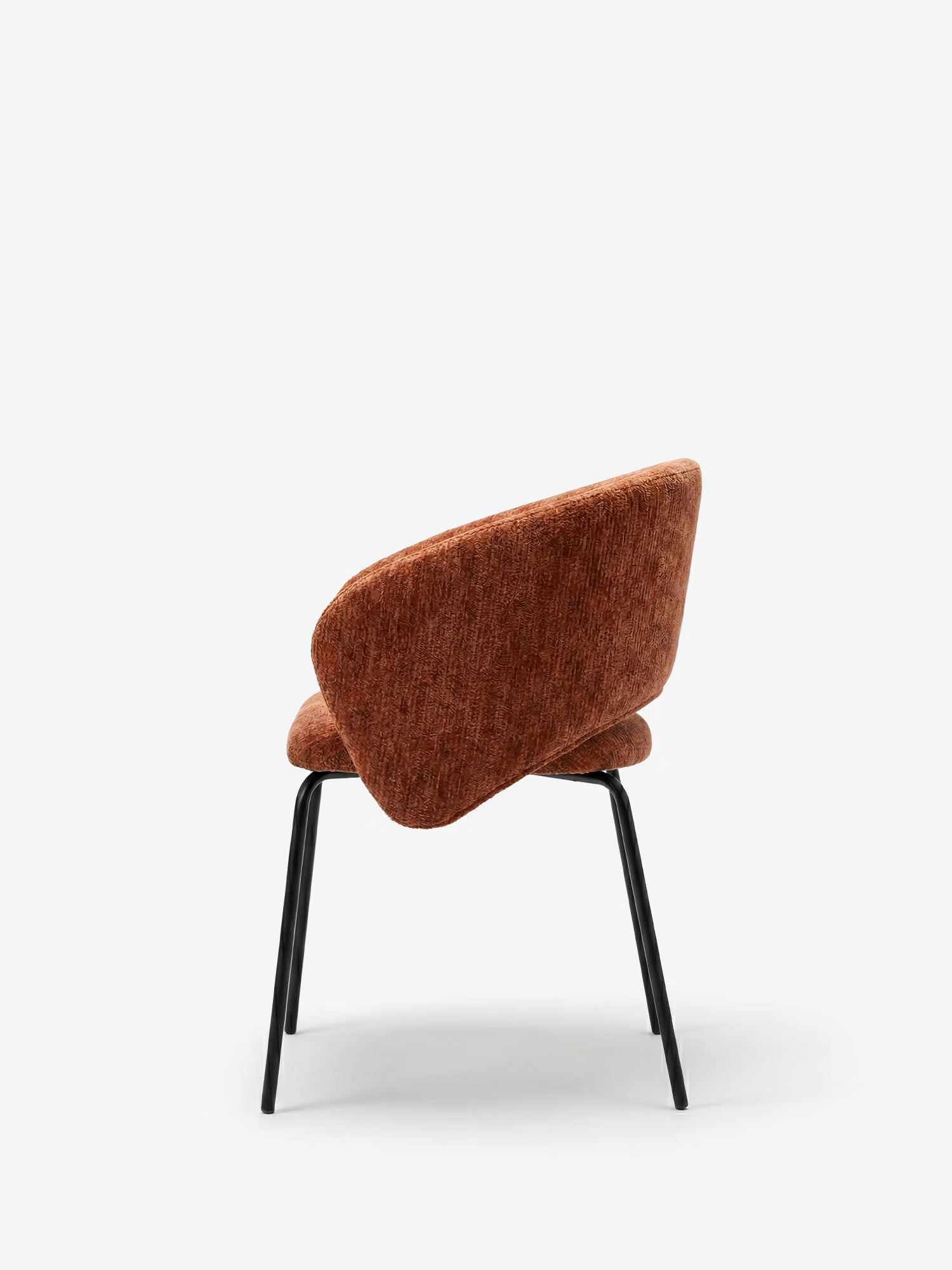 La sedia imbottita Fosca di Divani.Store è dotata di braccioli, tessuto color ruggine certificato OEKO-TEX®, sottili gambe in metallo nero e schienale e seduta imbottiti e curvi. Nella foto vista da dietro, mette in risalto il suo design moderno e minimalista.