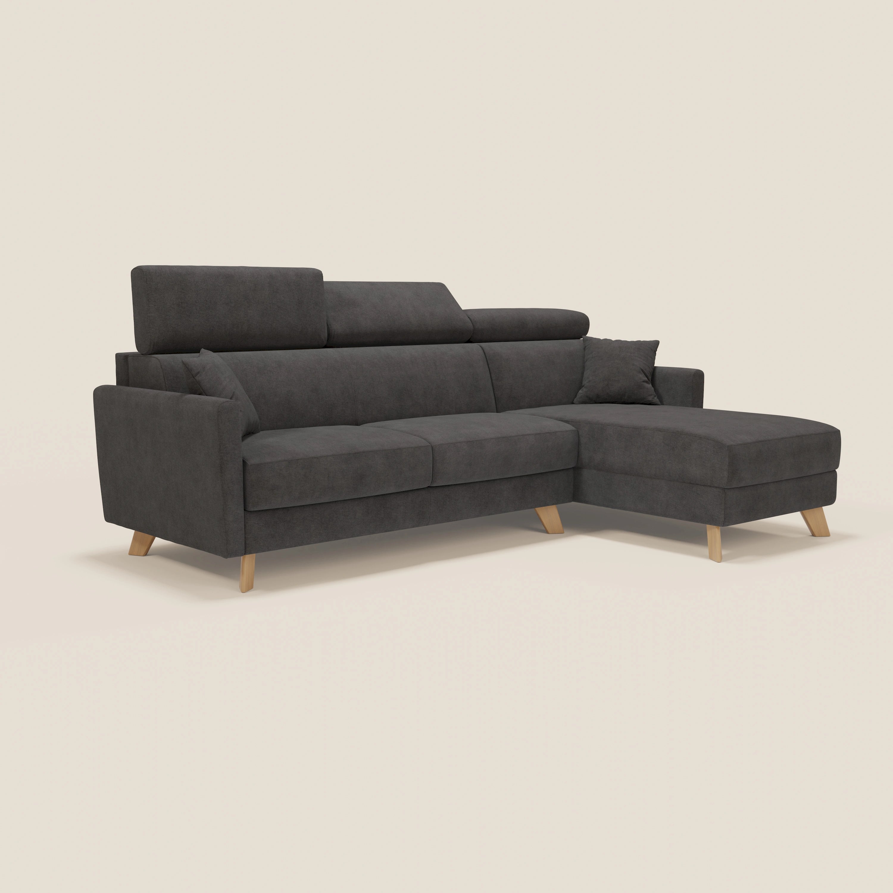 Il divano letto angolare sfoderabile Francy di Divani.Store, in tessuto smacchiabile T17 antracite, è dotato di chaise longue destra con contenitore, poggiatesta reclinabili, gambe in legno e viene fornito con un cuscino coordinato su sfondo bianco sporco.