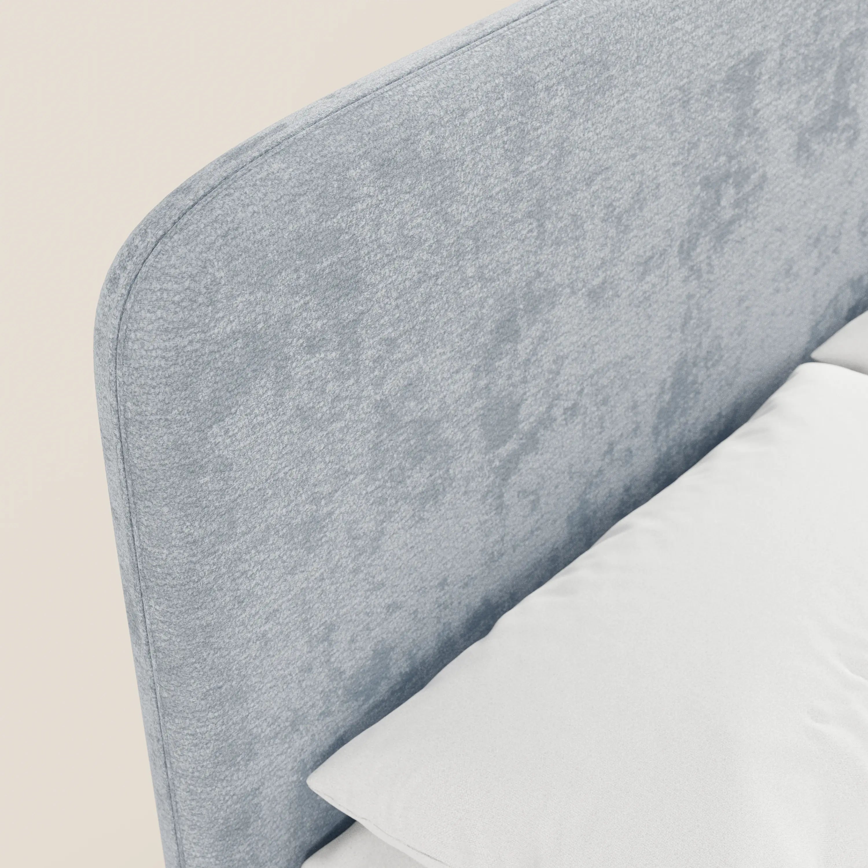 Un primo piano del letto KAELOS minimal imbottito di Letti.store, caratterizzato da una testiera in tessuto ciniglia grigio chiaro con angoli arrotondati, gambe alte e vano contenitore — ideale per una camera da letto moderna — su uno sfondo bianco sporco.