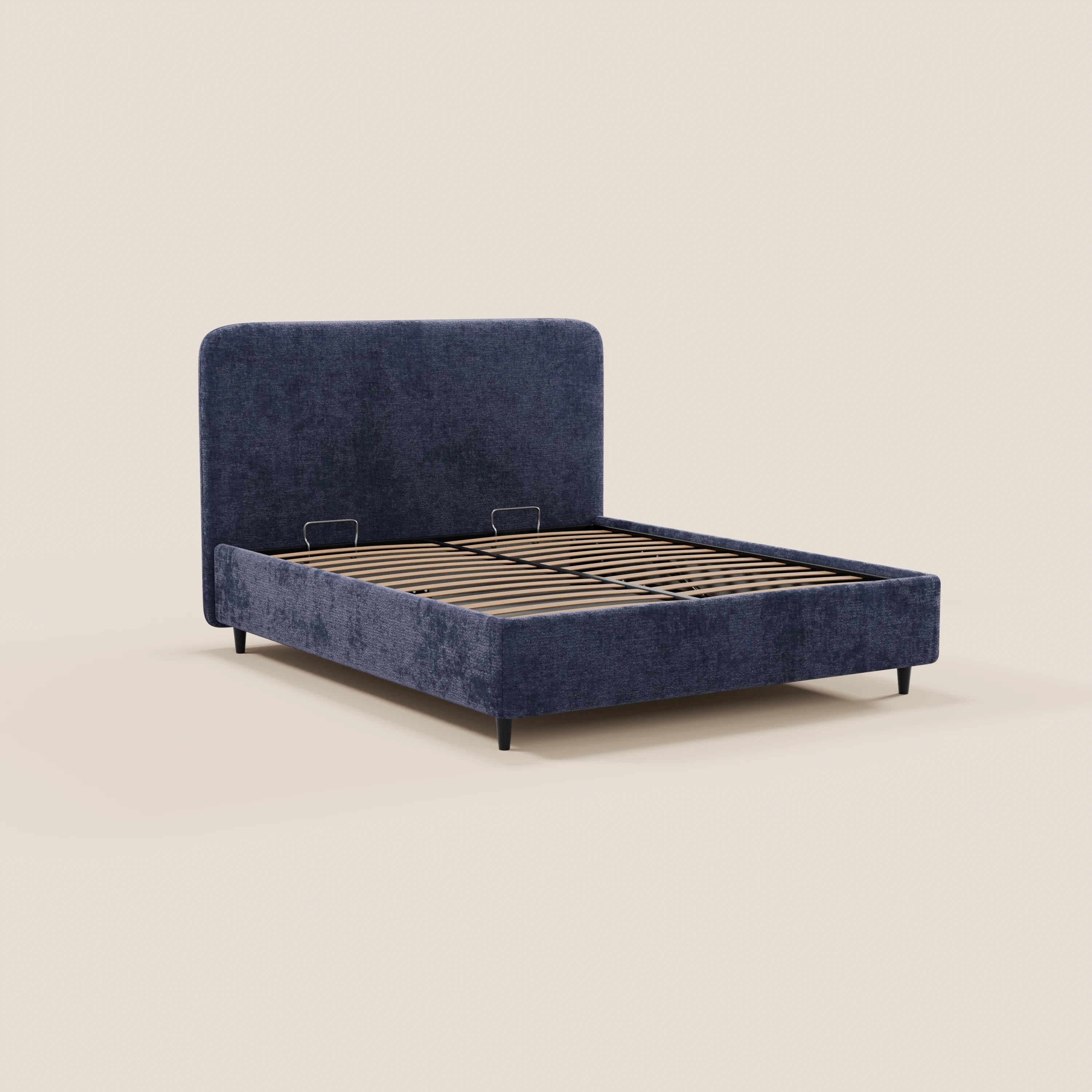 Il letto imbottito KAELOS minimal di Letti.store presenta una morbida testiera arrotondata in ciniglia blu scuro, gambe alte nere, base contenitore, doghe in legno per il sostegno e due supporti metallici per il materasso. Il tutto su uno sfondo beige chiaro a tinta unita.