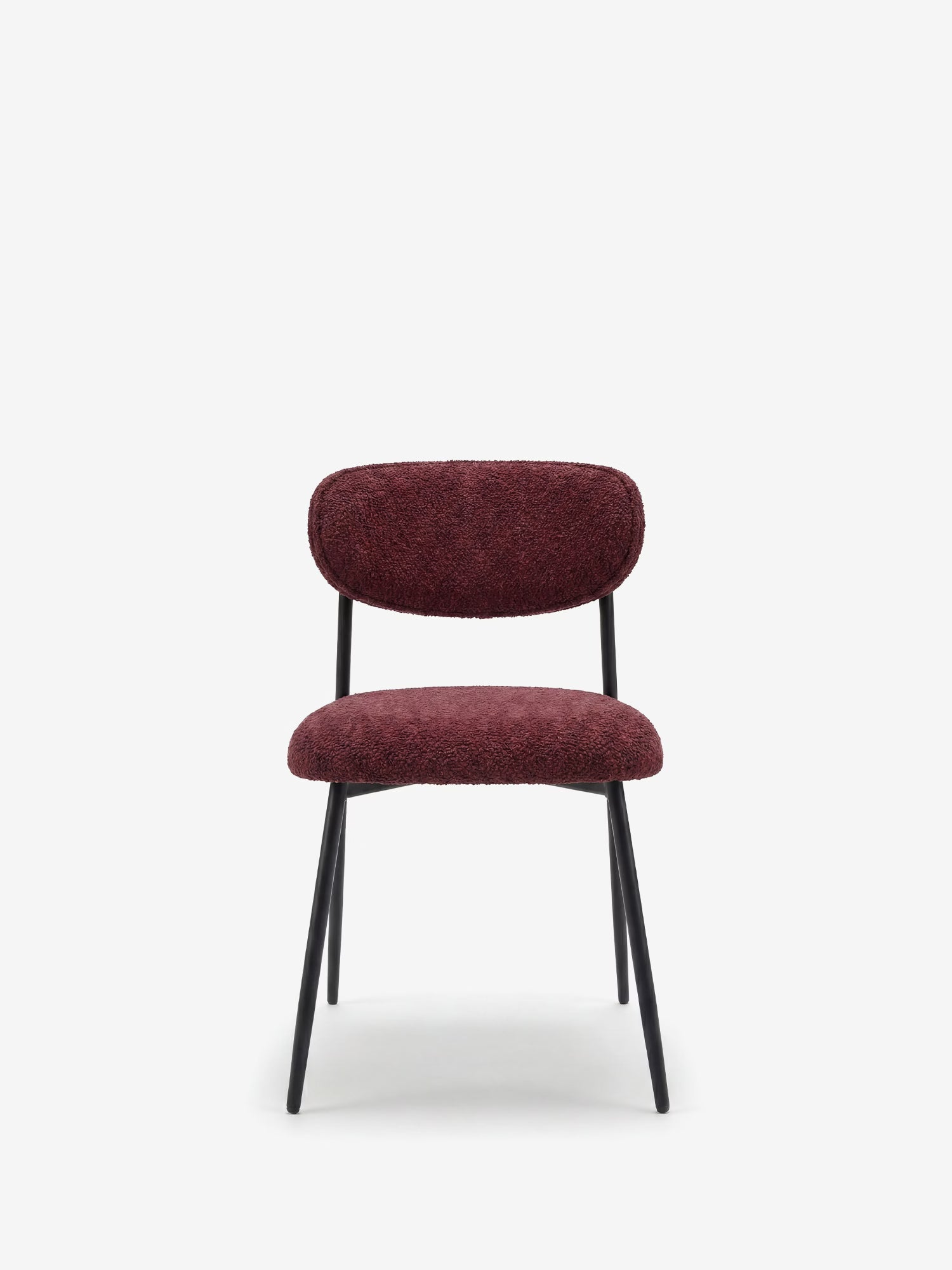 La sedia imbottita Luce in morbida ciniglia di Divani.Store presenta uno schienale e una seduta curvi in ciniglia color bordeaux intenso, sostenuti da sottili gambe in metallo nero che le conferiscono un look moderno sullo sfondo bianco.