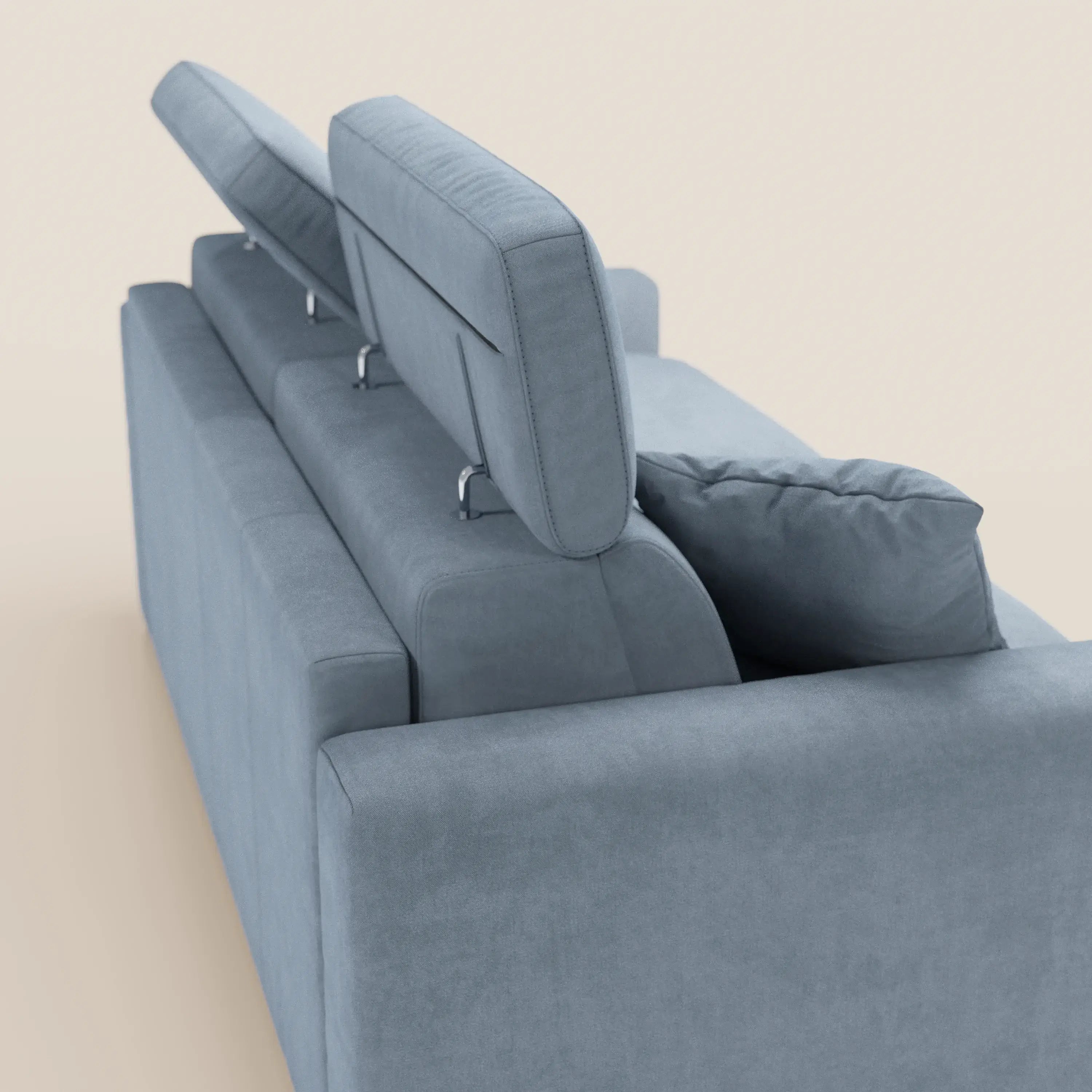 Il divano letto a 3 posti Maximus con materasso ALTO 20 cm di Divani.Store è raffigurato di retro in azzurro, con poggiatesta reclinabili regolabili in diverse angolazioni. Il tessuto smacchiabile certificato Oeko-Tex e il cuscino coordinato ne aumentano il comfort. Lo sfondo è beige a tinta unita.