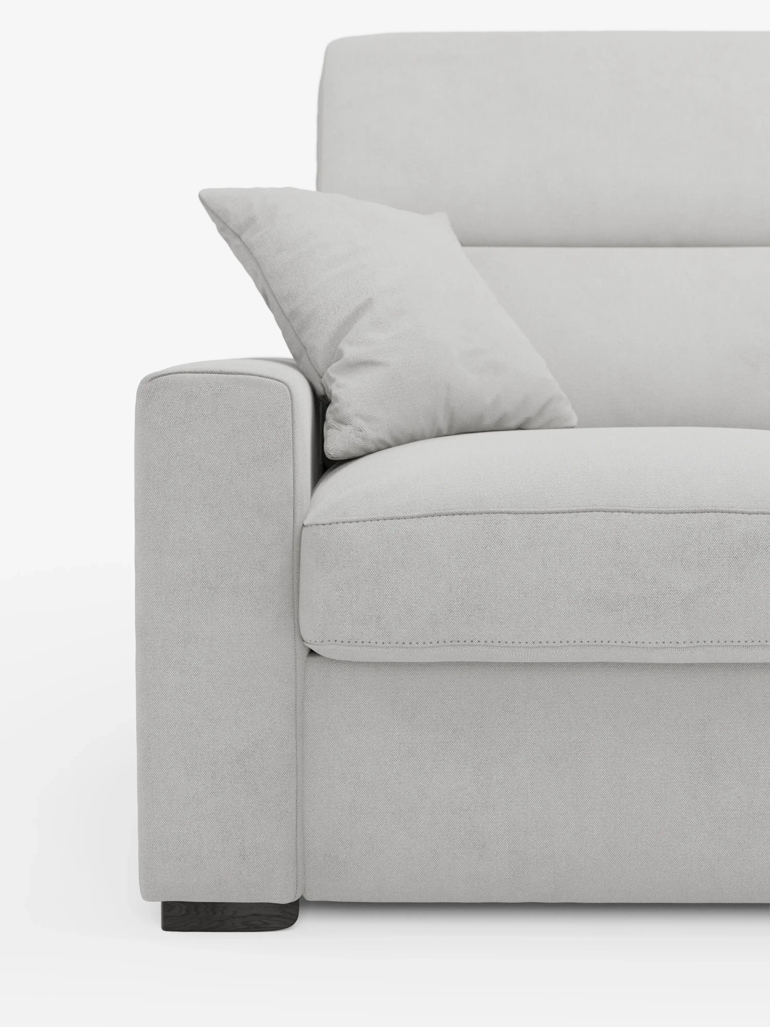 Primo piano del divano letto Maximus a 3 posti con materasso ALTO 20 cm di Divani.Store, in una moderna finitura grigio chiaro. L'immagine mette in risalto il bracciolo sinistro, parte della seduta imbottita e un cuscino coordinato. Caratterizzato da linee pulite e da un design minimalista, questo divano presenta cuciture a vista sui bordi e poggiatesta reclinabili. Rivestito in tessuto smacchiabile Oeko-Tex. Lo sfondo è bianco a tinta unita.