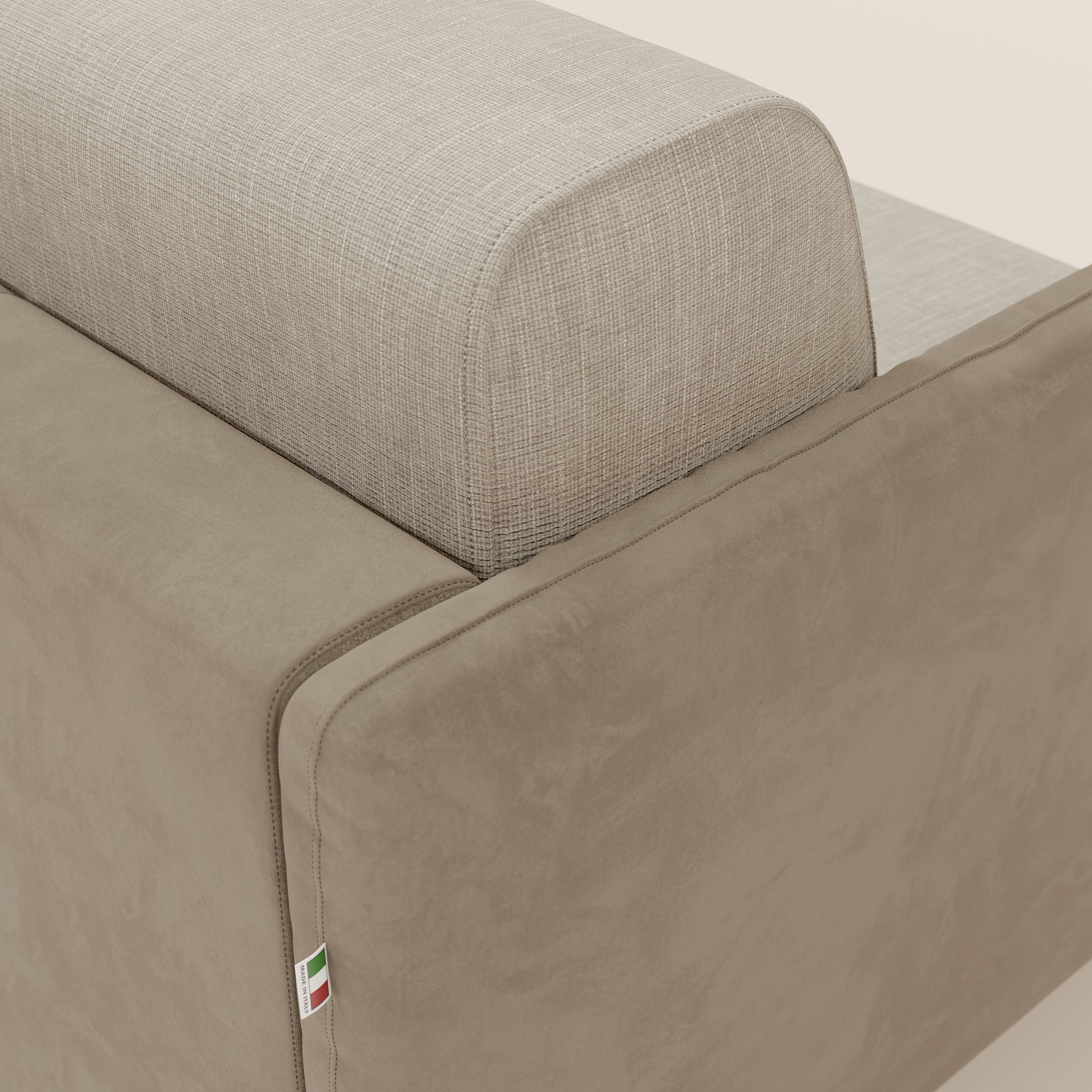Primo piano del divano letto Narciso di Divani.Store: lo schienale in elegante tessuto impermeabile T06 panna contrasta con i fianchi in microfibra color tortora. Una piccola etichetta con la bandiera italiana sottolinea l'angolo. Lo sfondo è bianco panna.