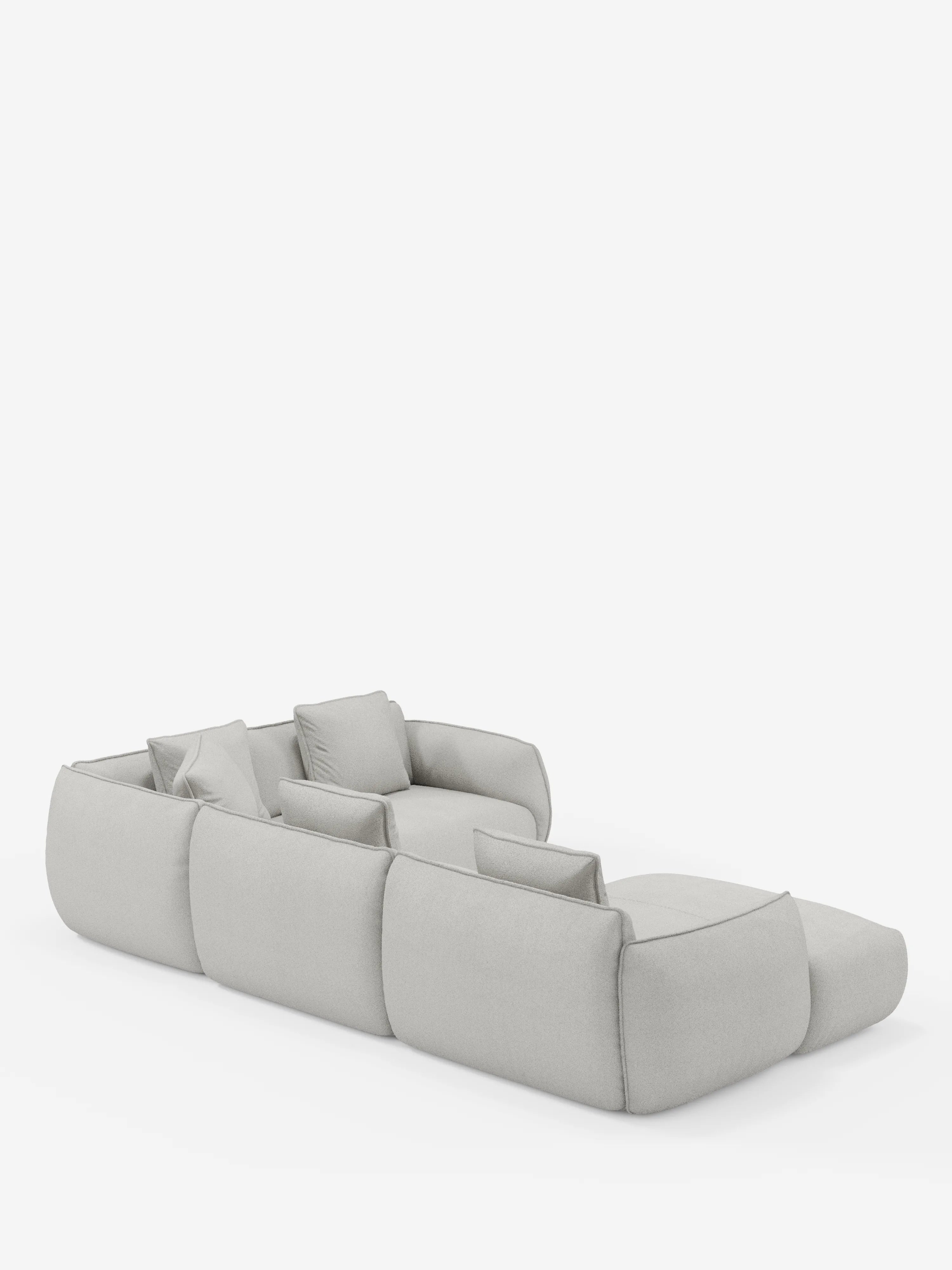 Un divano angolare panoramico componibile contemporaneo della linea Nimbus con penisola e angolo in tessuto smacchiabile T33 di Divani.Store, raffigurato dal lato posteriore sinistro in finitura grigio chiaro. Questo divano componibile Made in Italy presenta sedute ampie e basse, morbidi bordi arrotondati e sei cuscini di seduta con cuscini decorativi coordinati, il tutto su uno sfondo bianco a tinta unita. Il design minimalista è al tempo stesso accogliente ed elegante.
