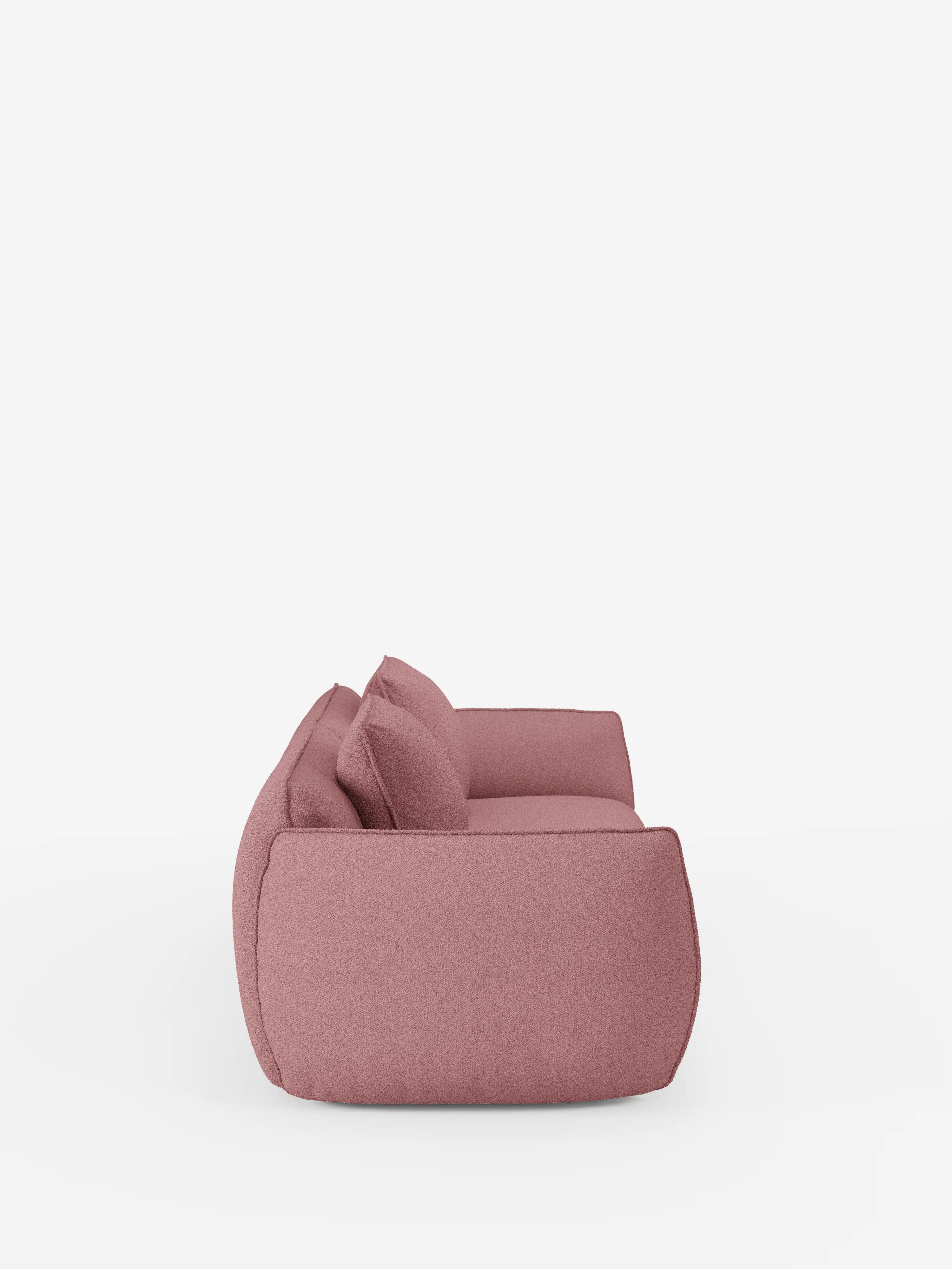 Vista laterale del divano Nimbus a 3 posti, modulare e componibile, da 250 cm di Divani.Store, caratterizzato da un morbido rivestimento sfoderabile rosa effetto cotone e resistente alle macchie (t33), bordi arrotondati e due cuscini coordinati. Questo divano moderno ha un'altezza ridotta da terra e presenta un design minimalista e accogliente su uno sfondo bianco a tinta unita.