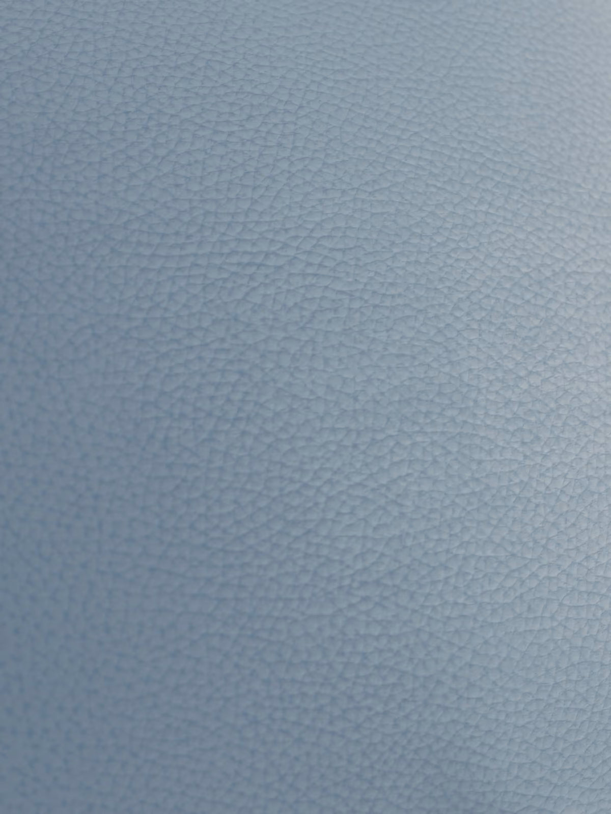Un primo piano della superficie blu e riccamente strutturata del “Chester – Divano Chesterfield in vera pelle spessorata a 2 e 3 posti” di Divani.Store rivela la grana fine e uniformemente distribuita, simile a ciottoli, caratteristica della pelle italiana di alta qualità. L’illuminazione soffusa accentua la texture delicata e la profondità del materiale: un segno distintivo dell’eleganza di questo divano artigianale Made in Italy.