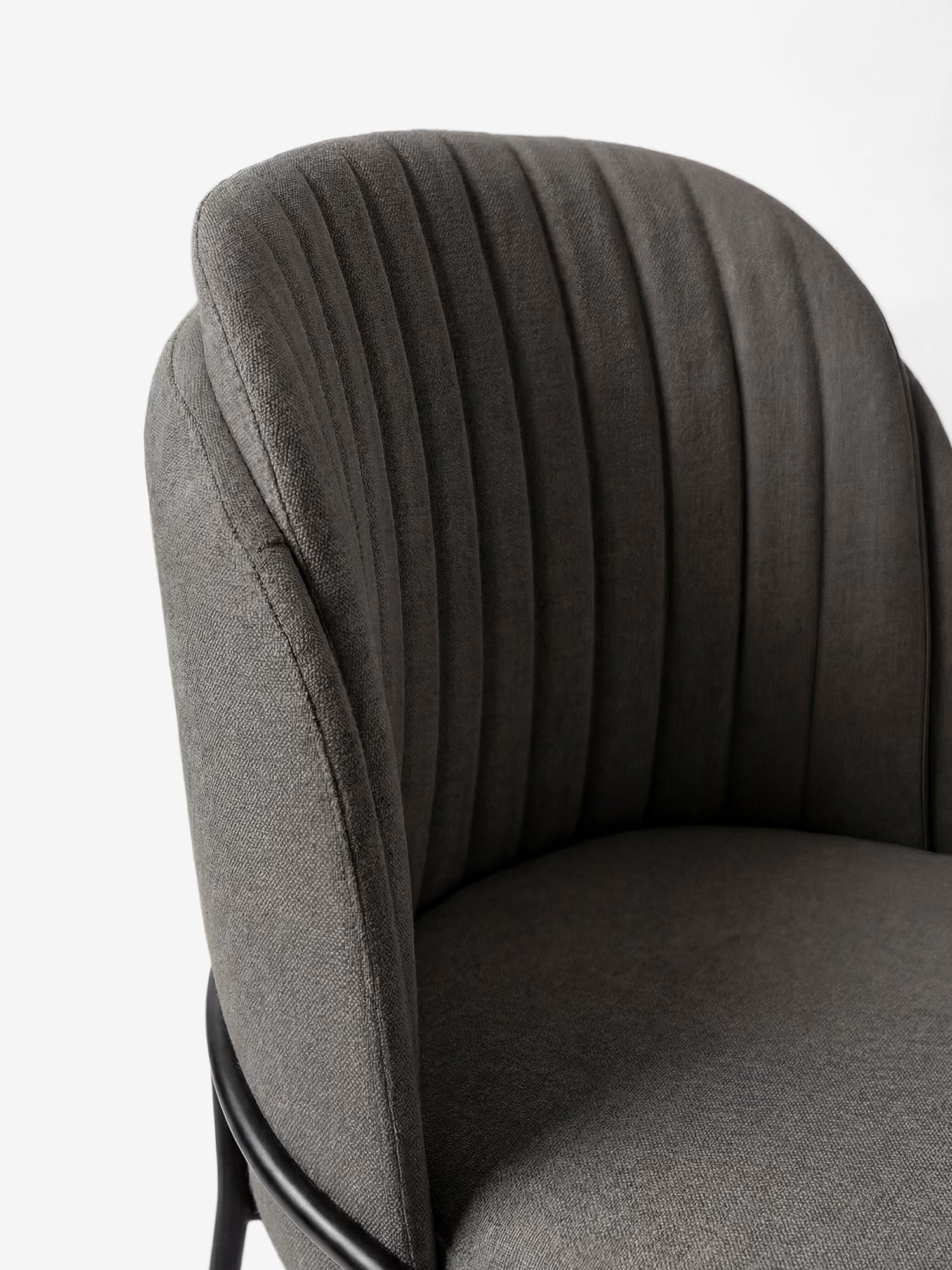 Primo piano della sedia imbottita "Plissè" in tessuto impermeabile di Divani.Store, che ne mette in risalto lo schienale curvo plissettato, la seduta liscia e le eleganti gambe in metallo nero su uno sfondo bianco.