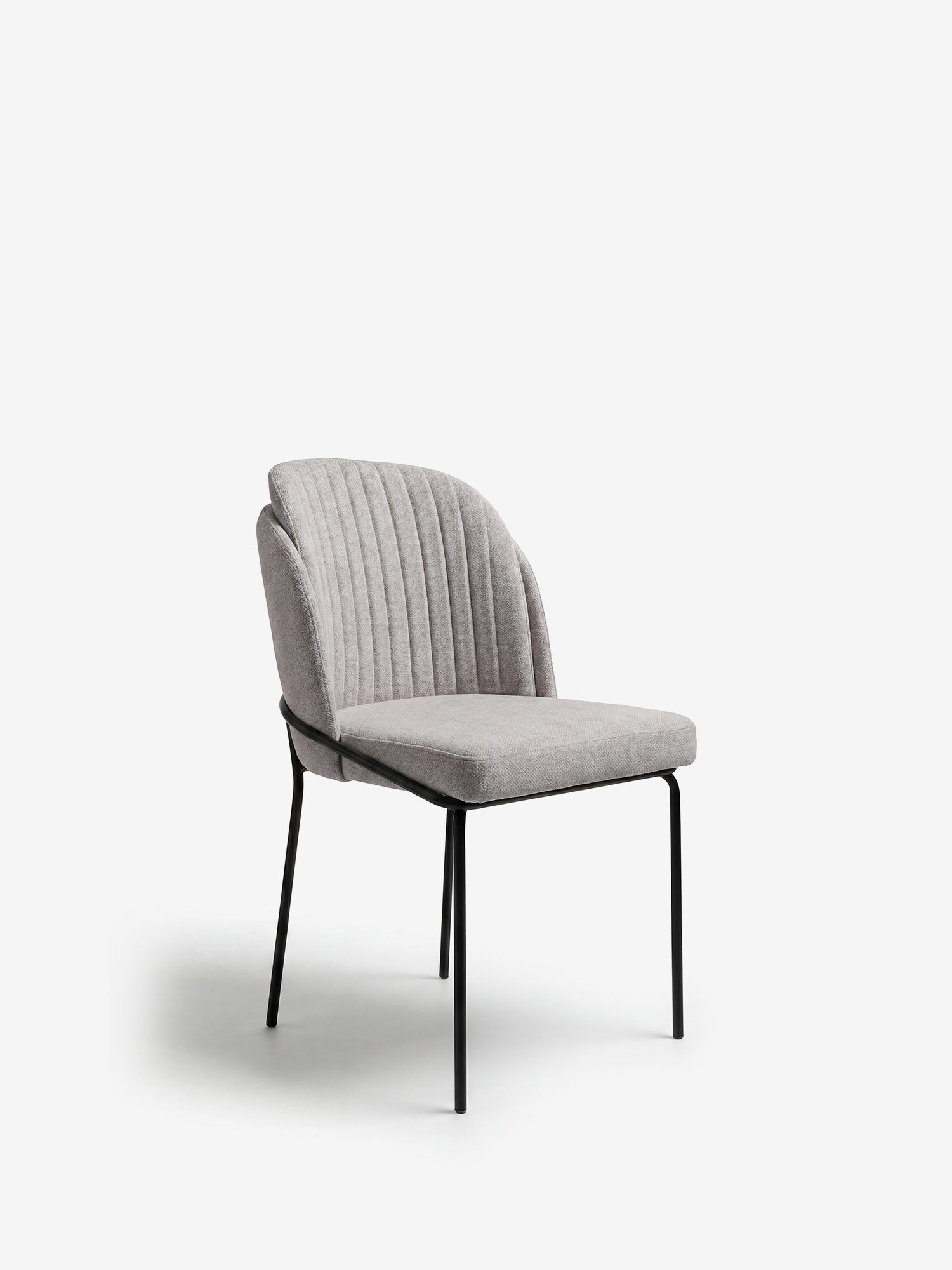 La sedia imbottita Plissè in tessuto impermeabile di Divani.Store presenta uno schienale plissettato e gambe in metallo nero. Elegante e moderna, la sedia è ritratta su sfondo bianco, con una leggera inclinazione verso destra.