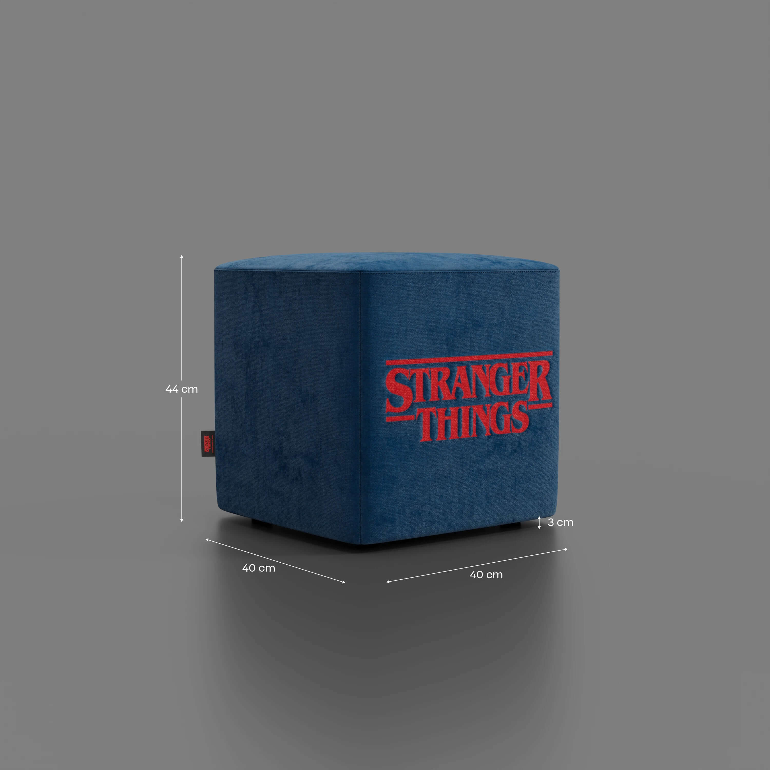 Il pouf Cube Stranger Things Edition di Divani.Store è un pouf in velluto blu antimacchia con scritte rosse, base grigia, targhetta laterale nera e misura 44x40x40 cm con uno spazio libero di 3 cm.