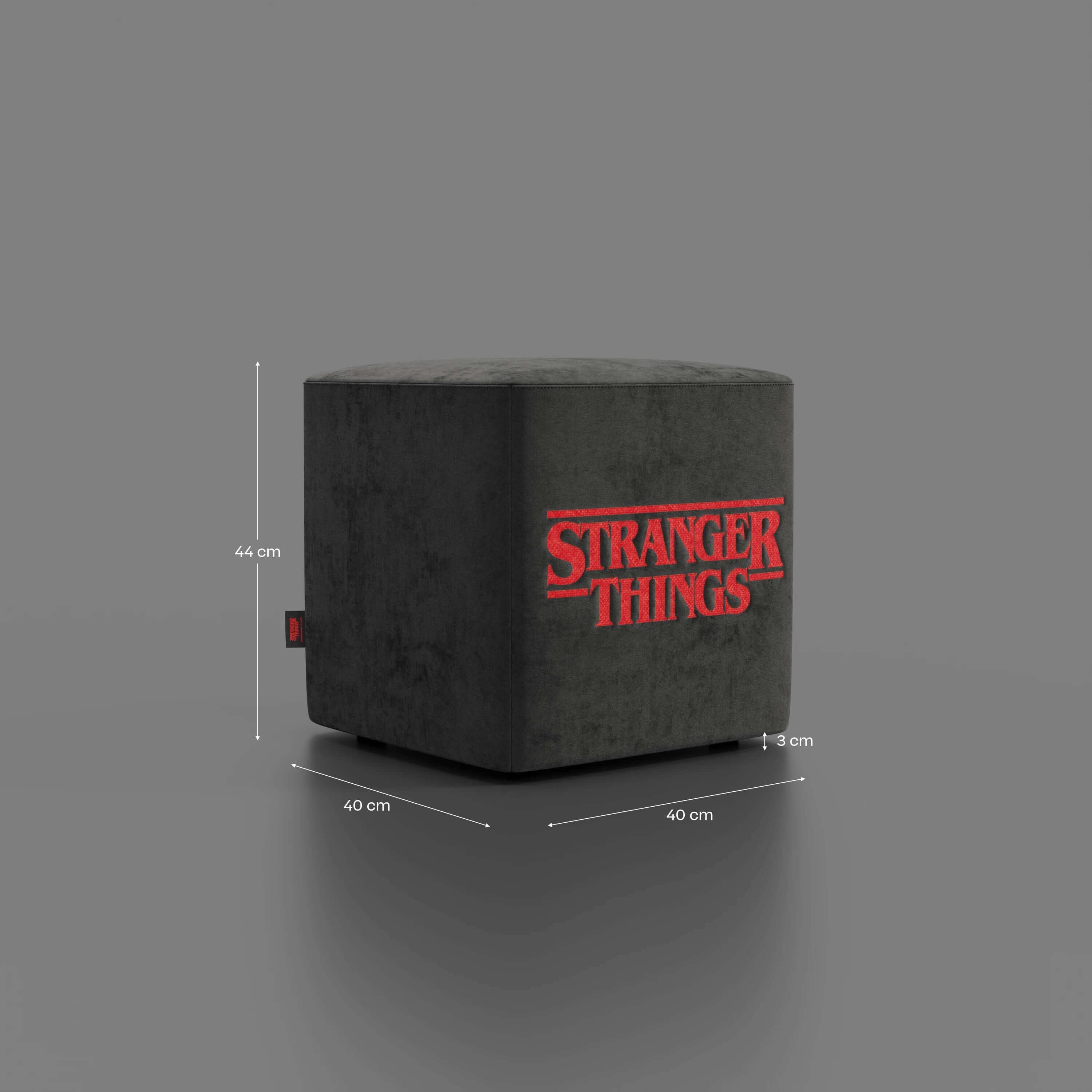 Il Pouf Cube Stranger Things Edition di Divani.Store è caratterizzato da un tessuto antracite antimacchia con scritte rosse. Questo elegante pouf misura 44 cm di altezza, 40 cm di larghezza e 40 cm di profondità, con uno sfondo grigio solido e linee di misurazione che ne evidenziano le dimensioni.