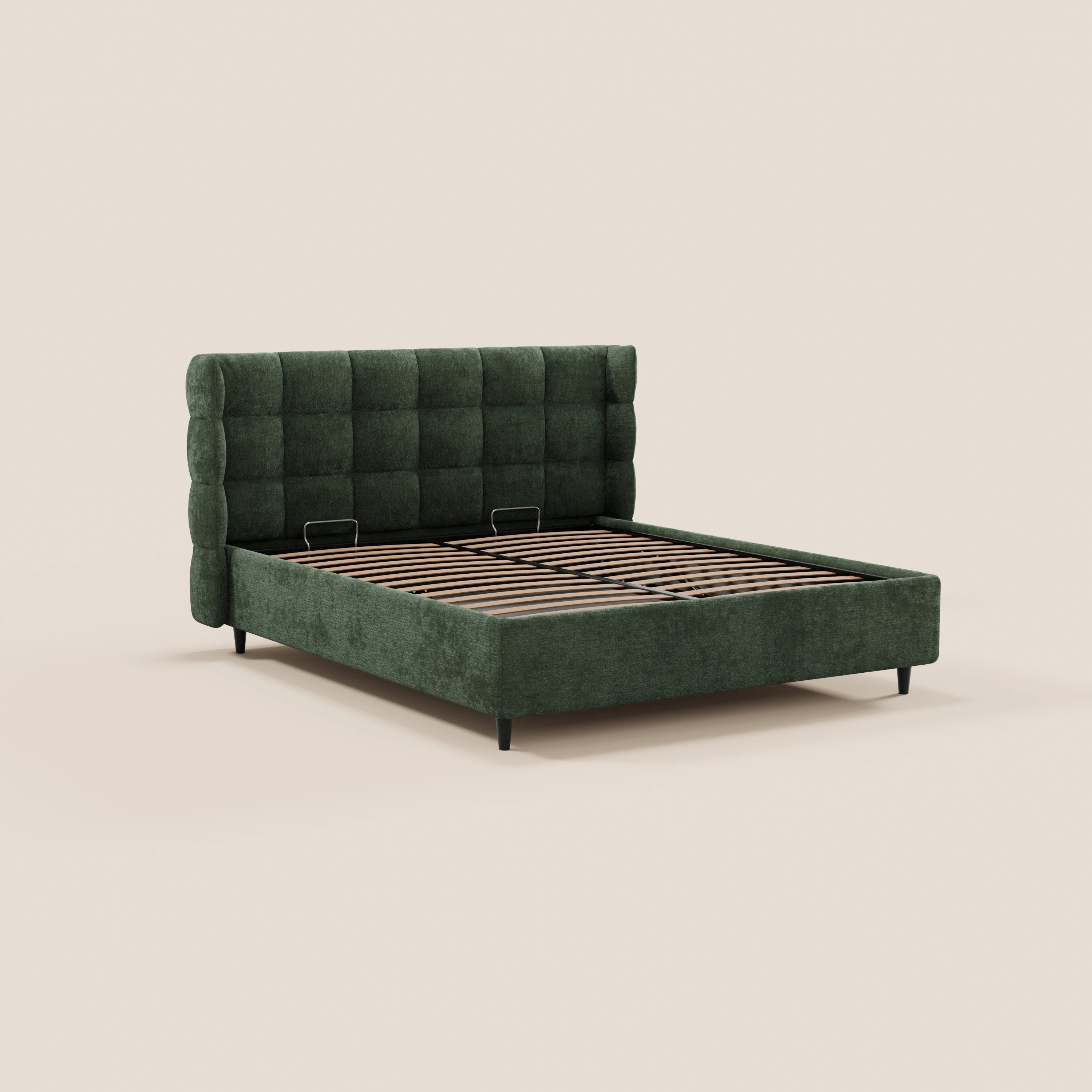 Il letto imbottito RAGNAR di Letti.store presenta una testiera alta e avvolgente con rivestimento capitonné in tessuto verde certificato Oeko-Tex®, fianchi bassi, gambe nere e doghe in legno a vista. Nell’immagine è raffigurato senza materasso né biancheria da letto su uno sfondo beige chiaro.