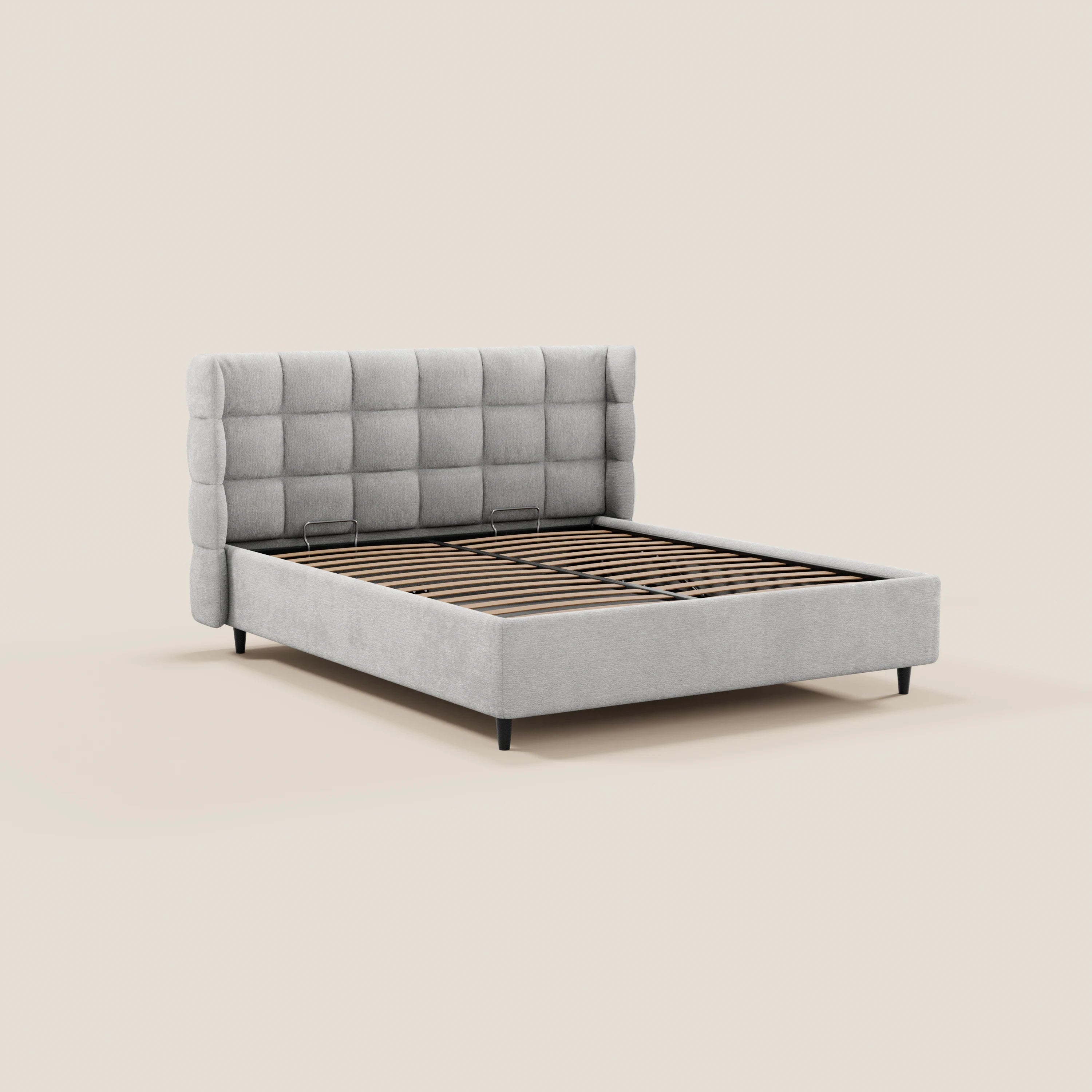 Il letto imbottito RAGNAR di Letti.store è realizzato con un tessuto grigio chiaro certificato Oeko-Tex®, una testiera avvolgente capitonné trapuntata, sponde imbottite in tinta, gambe nere e doghe in legno; nella foto è raffigurato senza materasso né biancheria da letto su uno sfondo beige chiaro.