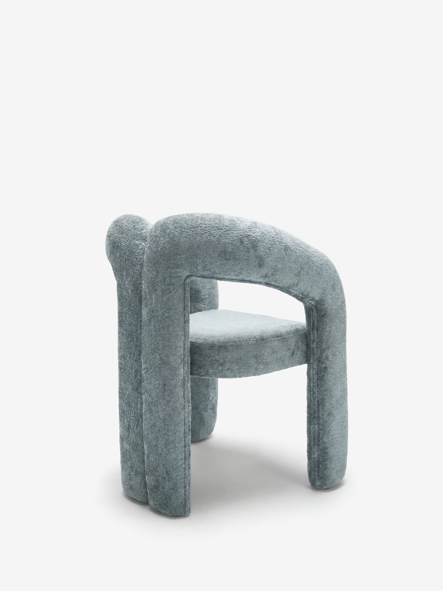 La sedia di design Sibilla di Divani.Store è interamente rivestita in morbido tessuto azzurro e presenta uno schienale arrotondato, braccioli ricurvi e gambe cilindriche massicce, che le conferiscono un aspetto scultoreo e armonioso sullo sfondo bianco.
