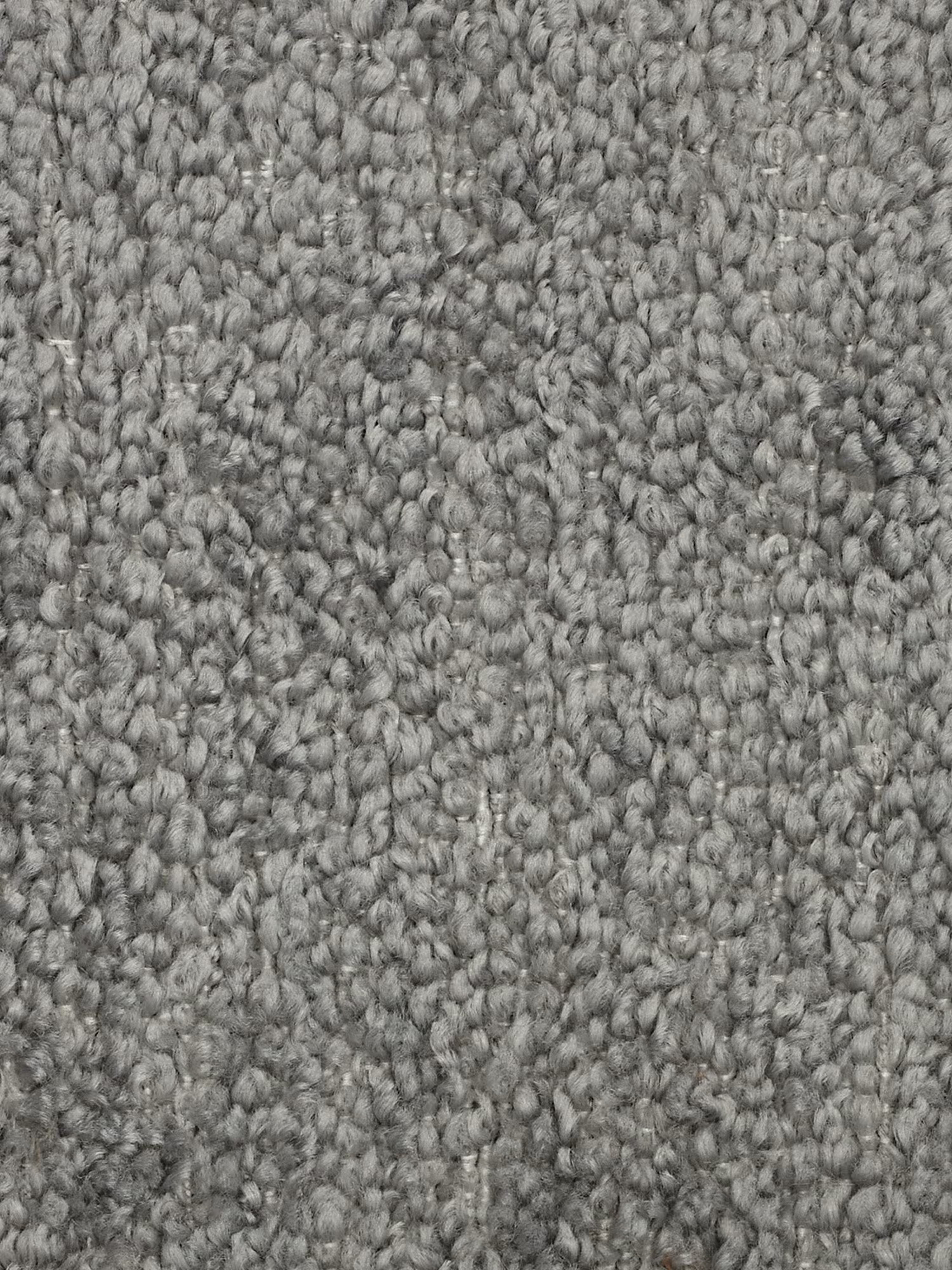 Primo piano di un tappeto grigio a pelo riccio con trama in rilievo. Le fibre formano piccoli anelli arrotondati, creando una superficie densa e morbida: una base ideale per qualsiasi divano modulare. Le varie sfumature di grigio aggiungono profondità e varietà, mettendo in risalto il motivo a trama fitta e l’aspetto soffice del tappeto, che si abbina perfettamente a un divano moderno negli spazi abitativi contemporanei.