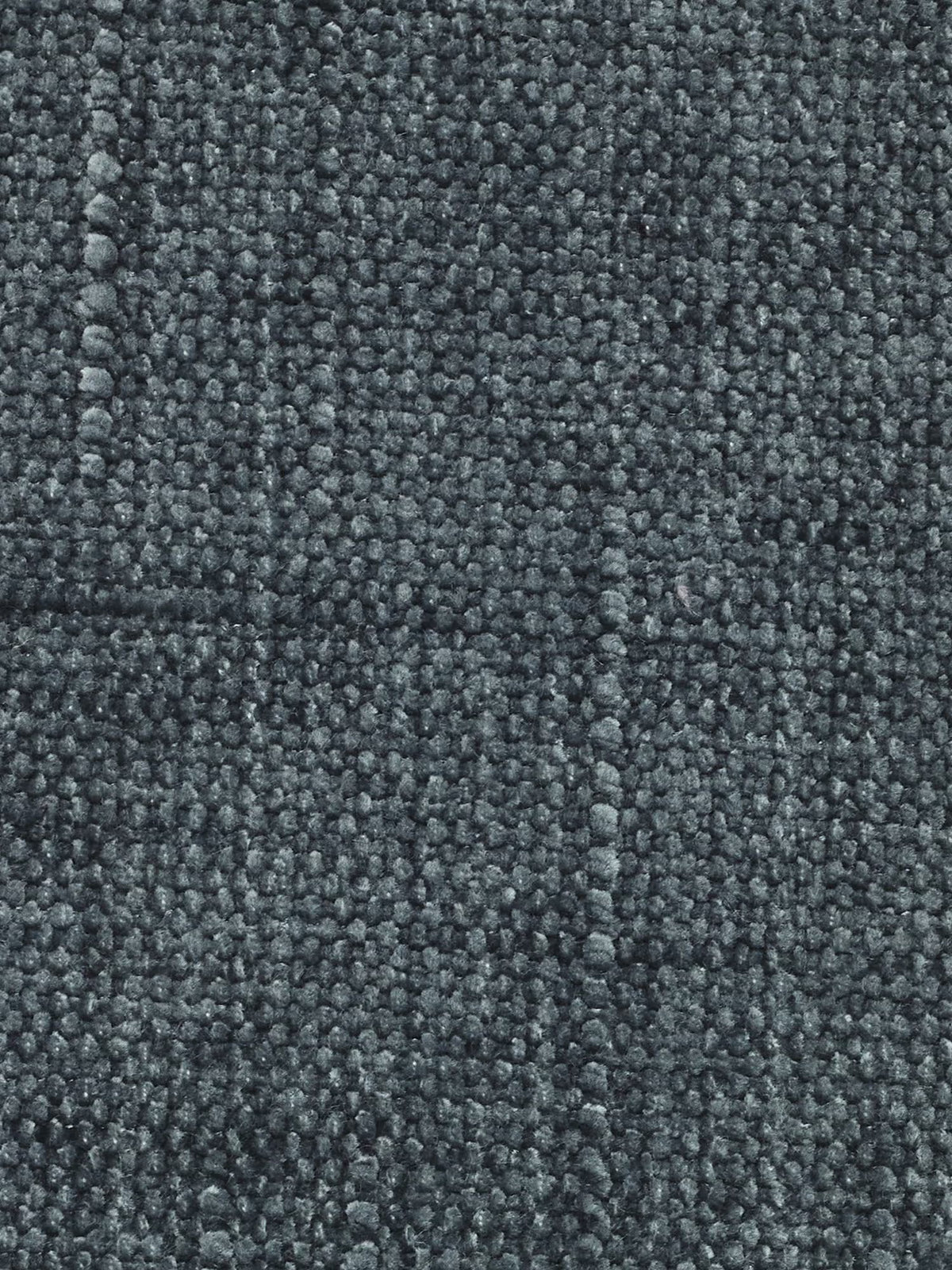 Primo piano di un tappeto in tessuto jacquard grigio scuro dalla trama ruvida, con un motivo a riccioli dalla trama fitta. La superficie appare morbida e caratterizzata da sfumature delicatamente variegate, con cuciture a vista che ne esaltano l’aspetto sofisticato: perfetta da abbinare al divano letto angolare Pegaso con poggiatesta reclinabili e penisola contenitore in tessuto jacquard smacchiabile T22 di Divani.Store.