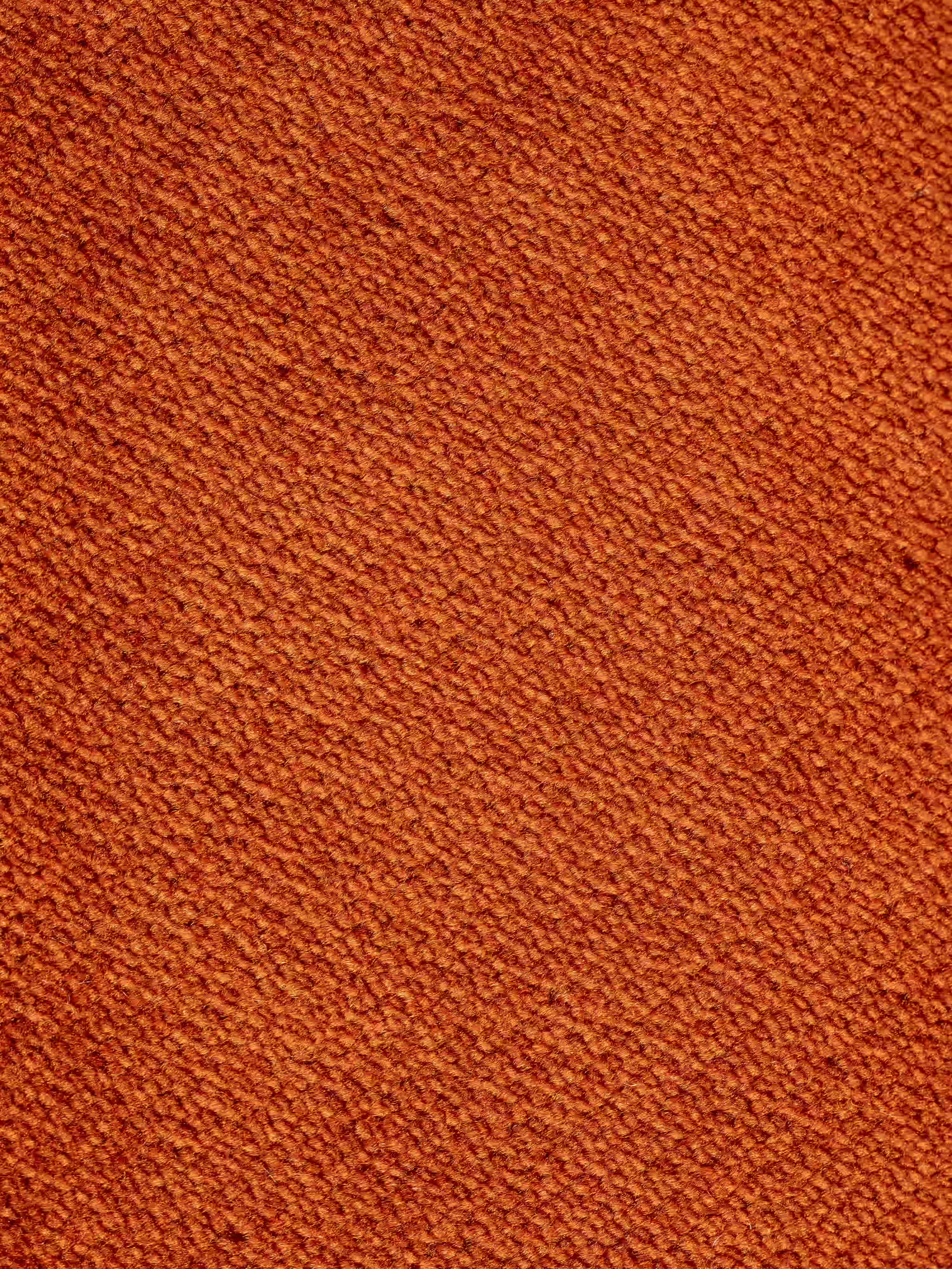 Primo piano del divano angolare con penisola e sedute estensibili “Michelangelo” di Divani.Store, caratterizzato da un raffinato tessuto smacchiabile color arancione effetto vellutino T30. Il tessuto presenta una trama fitta e compatta, tipica delle sedute estensibili e delle chaise longue di alta qualità, con un colore uniforme e una superficie leggermente ruvida, creata da piccole fibre distribuite in modo regolare su tutta la superficie.