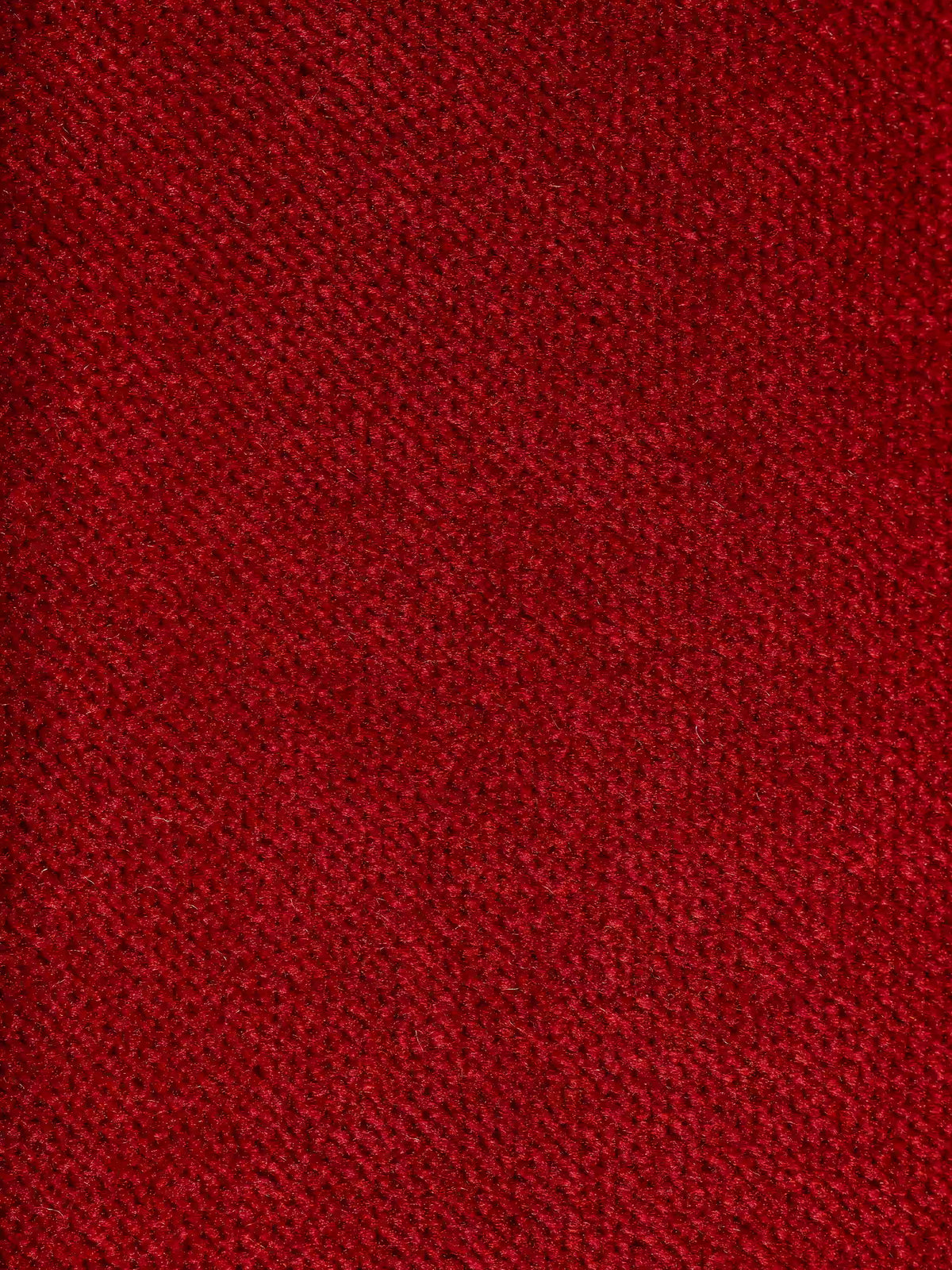 Primo piano del raffinato rivestimento in tessuto effetto velluto smacchiabile T30 in un rosso intenso, che presenta una trama morbida e leggermente felpata con un delicato motivo intrecciato. Il gioco di luci e ombre sulla superficie ne esalta la profondità e il fascino visivo, riflettendo la raffinata maestria artigianale italiana del divano letto di design Capri con piedini alti e poggiatesta reclinabili di Divani.Store.