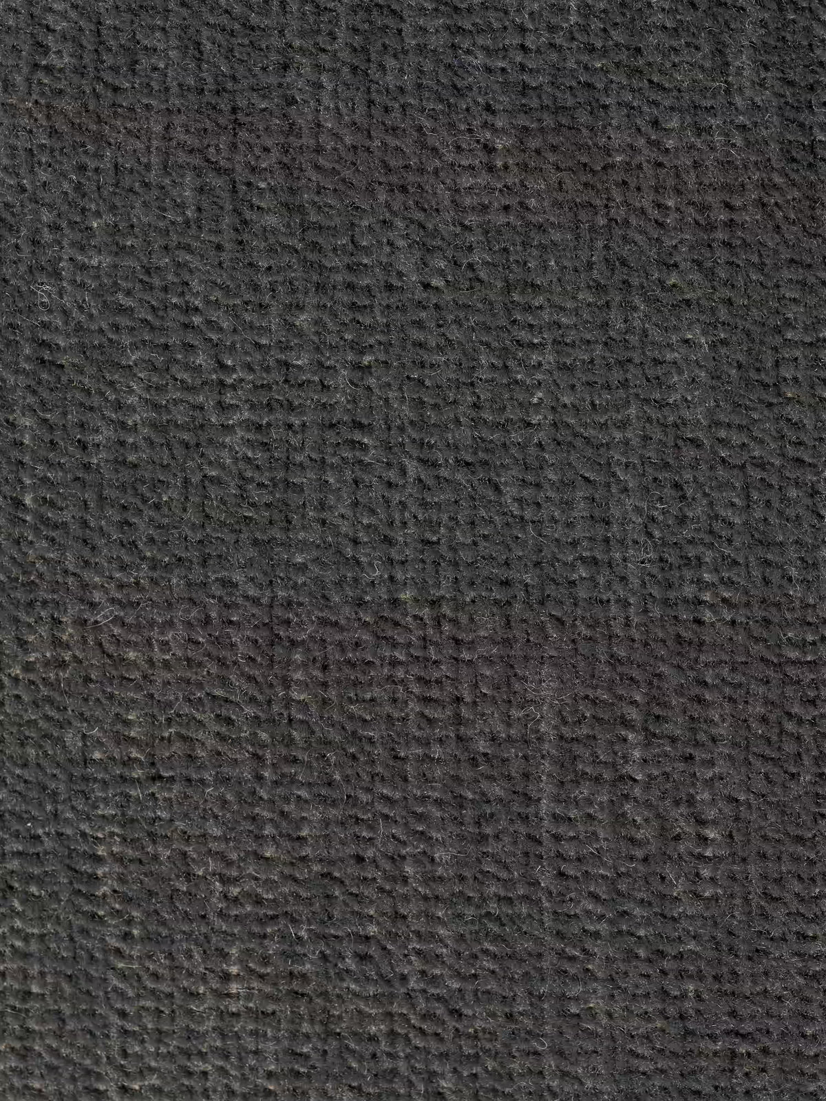 Primo piano del tessuto T31 grigio scuro smacchiabile a trama ruvida della poltrona letto Rift di Divani.Store, con materasso alto 24 cm e memory foam, che ne mette in risalto i piccoli motivi intrecciati a griglia e le sottili variazioni di tonalità. Il materiale appare resistente, con fibre a vista e una finitura opaca: perfetto per questa poltrona letto dal design minimalista, dotata di uno schienale mobile che garantisce un comfort versatile.