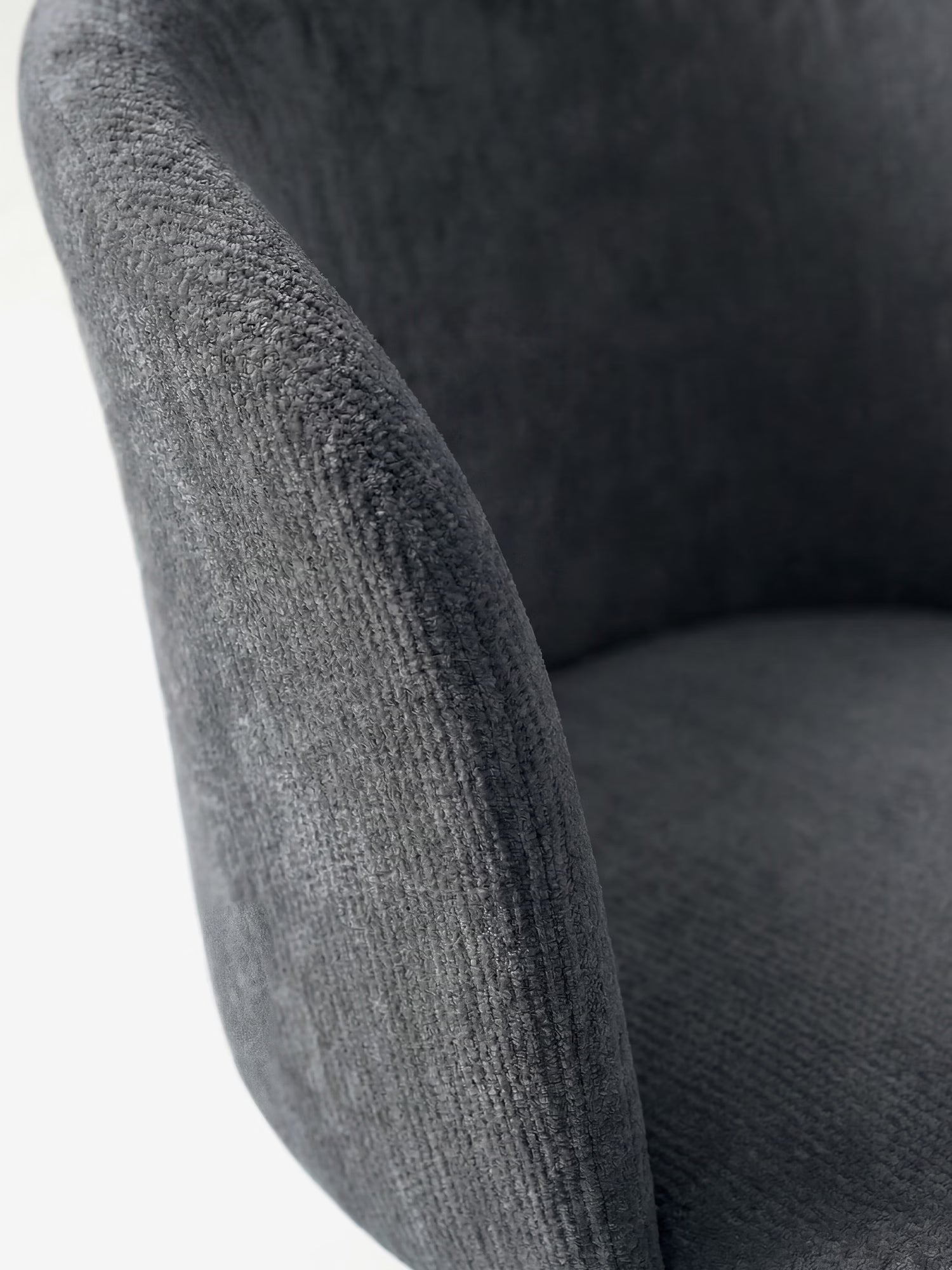 Primo piano della poltrona Talia Sedia moderna di Divani.Store in ciniglia grigio scuro certificata OEKO-TEX®, caratterizzata da uno schienale curvo e da una base imbottita. Il tessuto morbido e le linee armoniose ne esaltano il comfort e il design contemporaneo.
