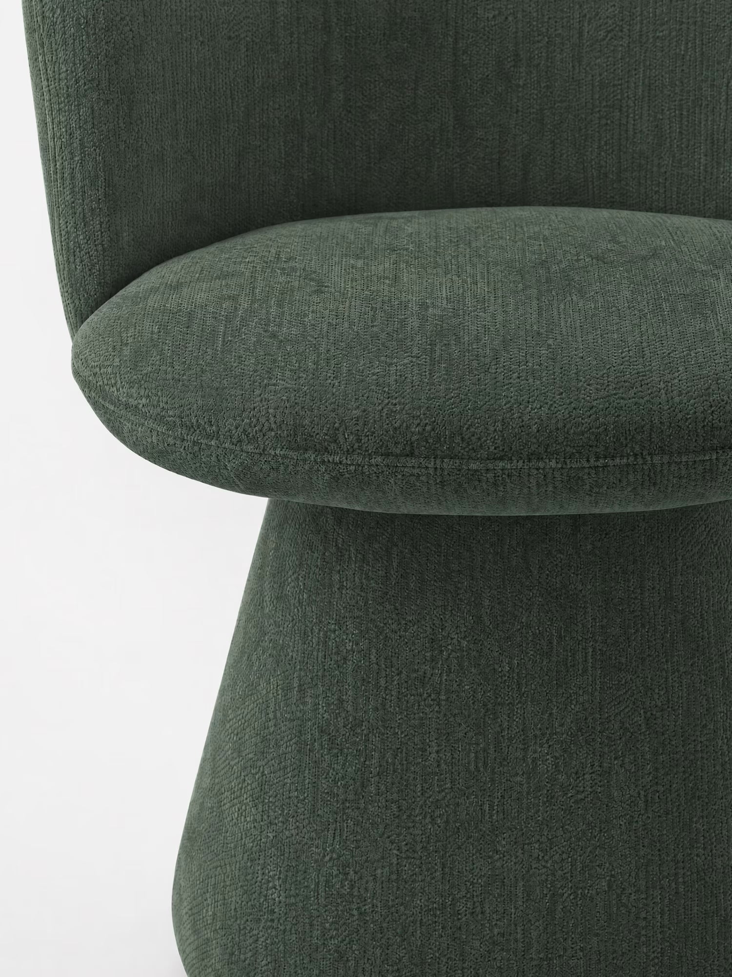 Primo piano della sedia moderna imbottita Talia di Divani.Store, rivestita in morbido tessuto ciniglia verde scuro certificato OEKO-TEX®, con schienale curvo, ampia seduta arrotondata e base rivestita in tessuto coordinato, su uno sfondo bianco a tinta unita.