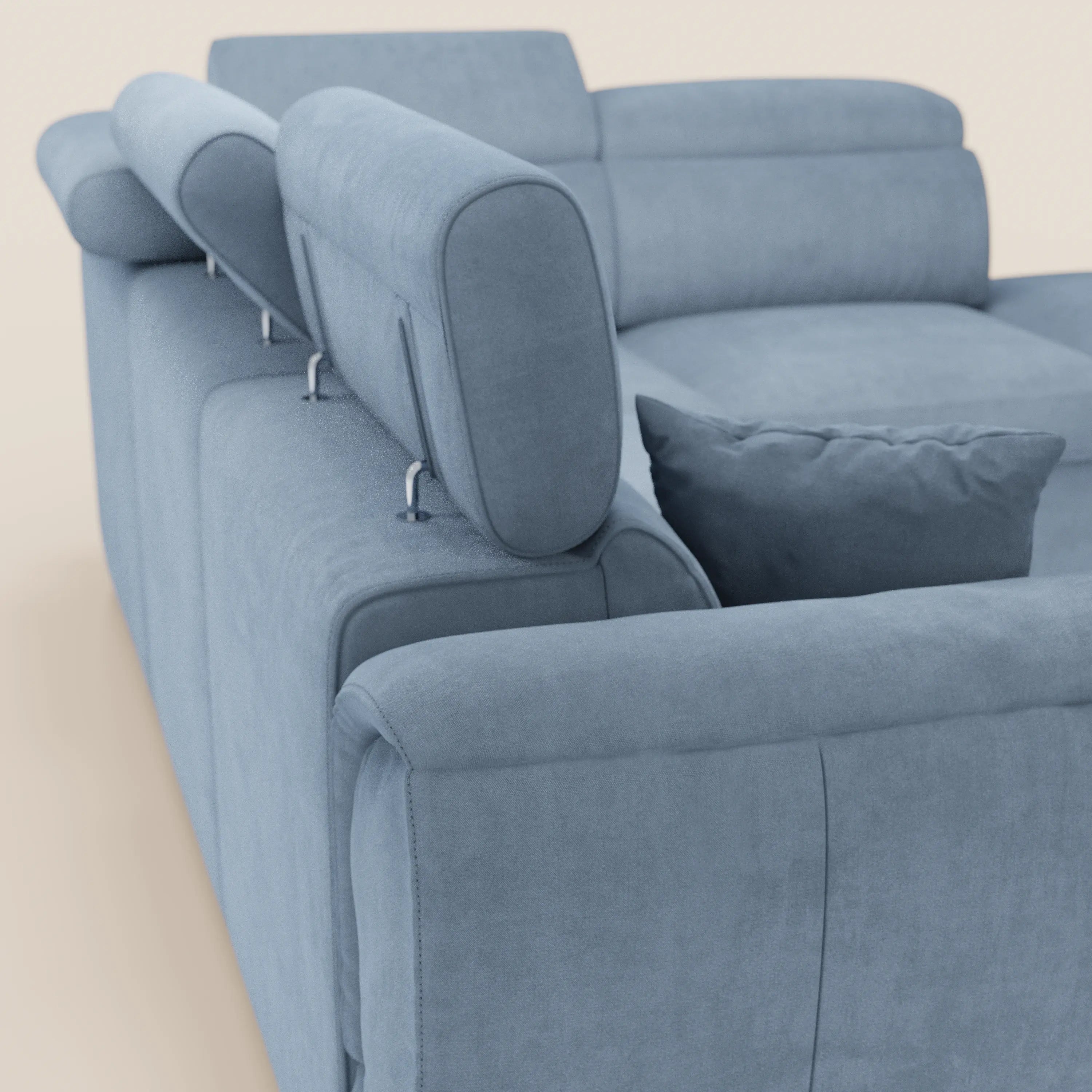 Un primo piano del divano angolare reversibile Titano di Divani.Store, dotato di poggiatesta reclinabili, un cuscino blu abbinato e un morbido tessuto Oeko-Tex® resistente alle macchie. Il suo design moderno si caratterizza per le linee pulite e l'imbottitura soffice.
